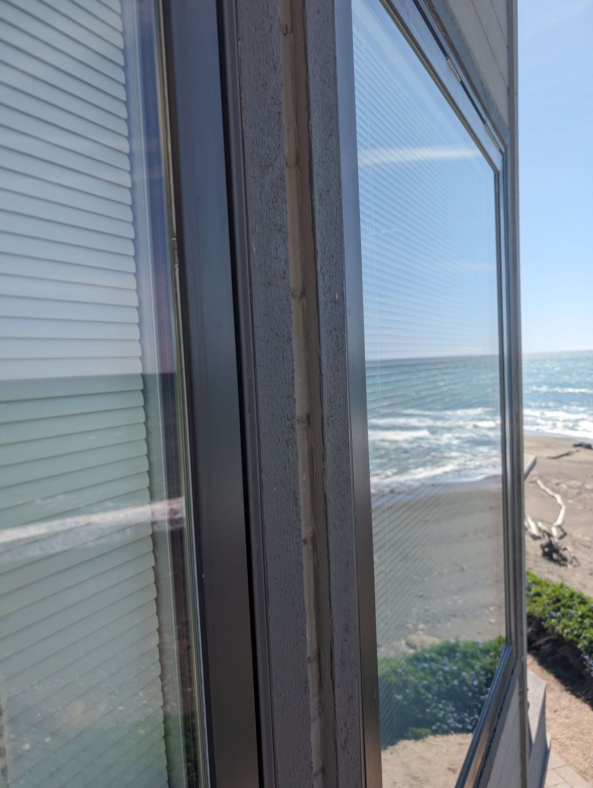 A view of the ocean from a window with blinds