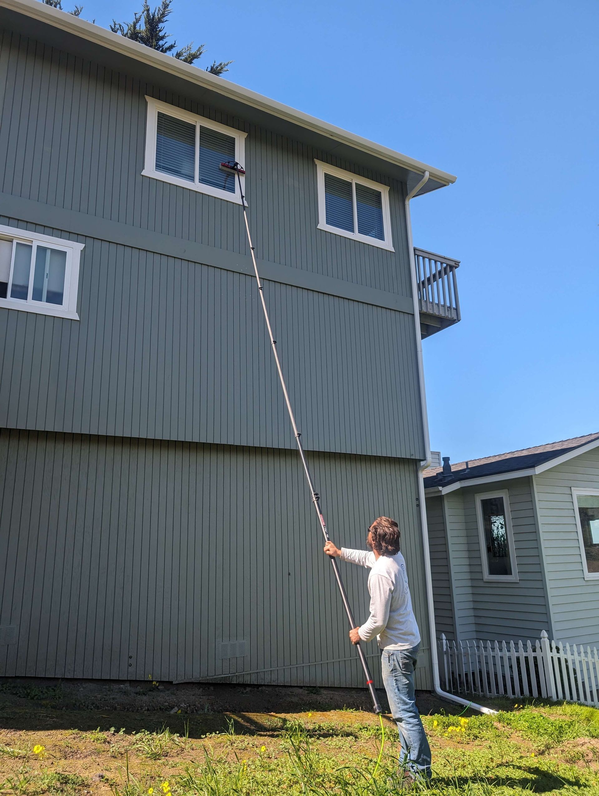 A man is cleaning the windows of a house with a ladder.