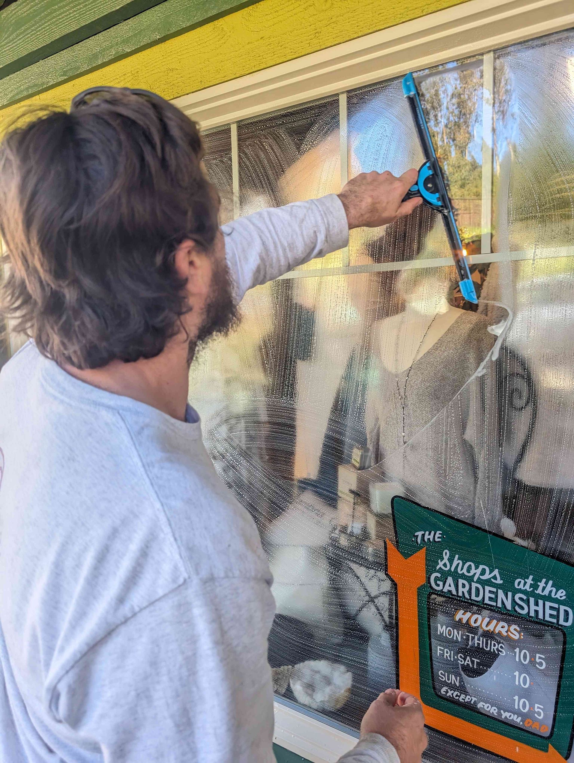 A man is cleaning a window with a squeegee.