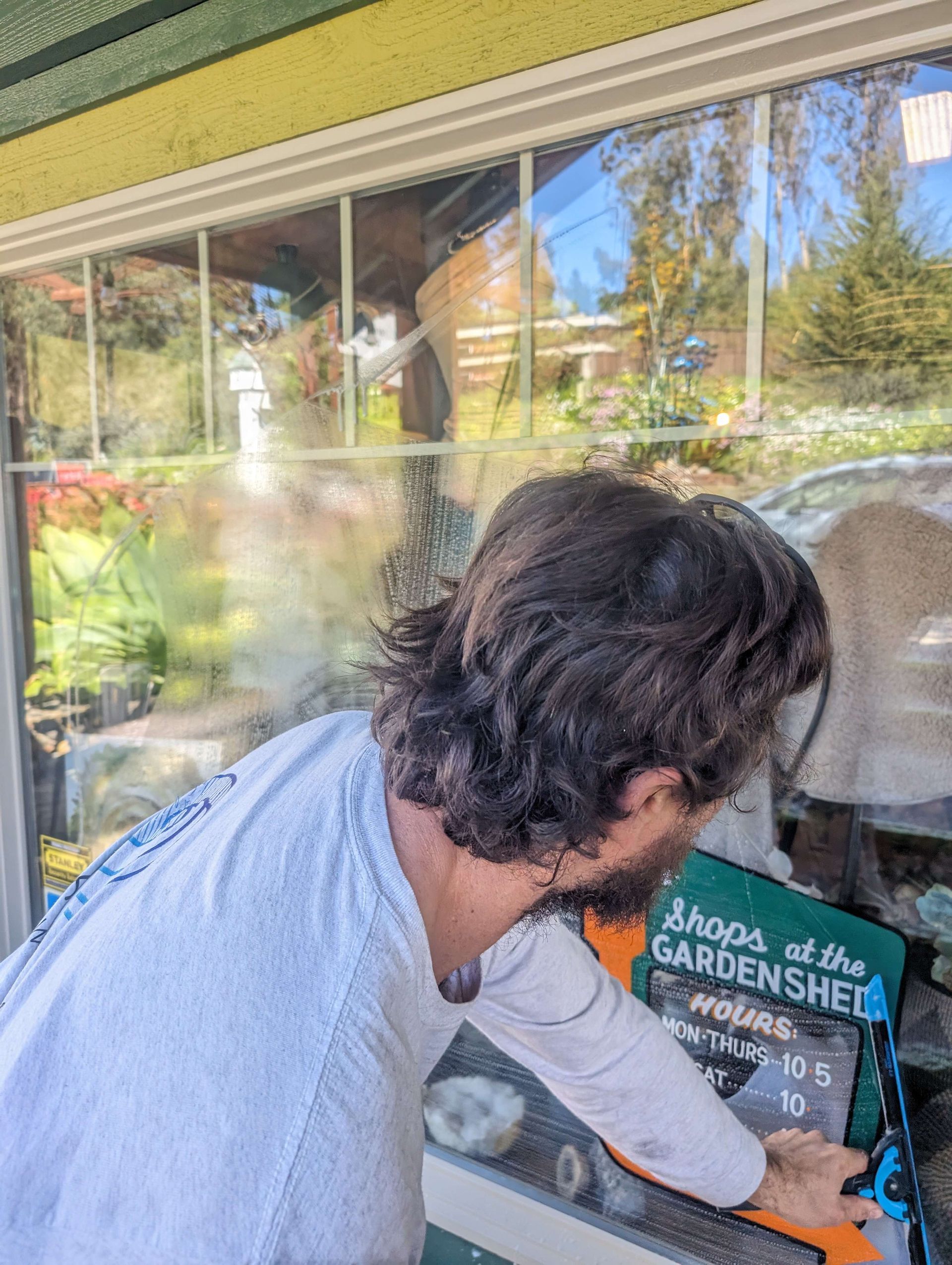 A man with a beard is standing in front of a window.