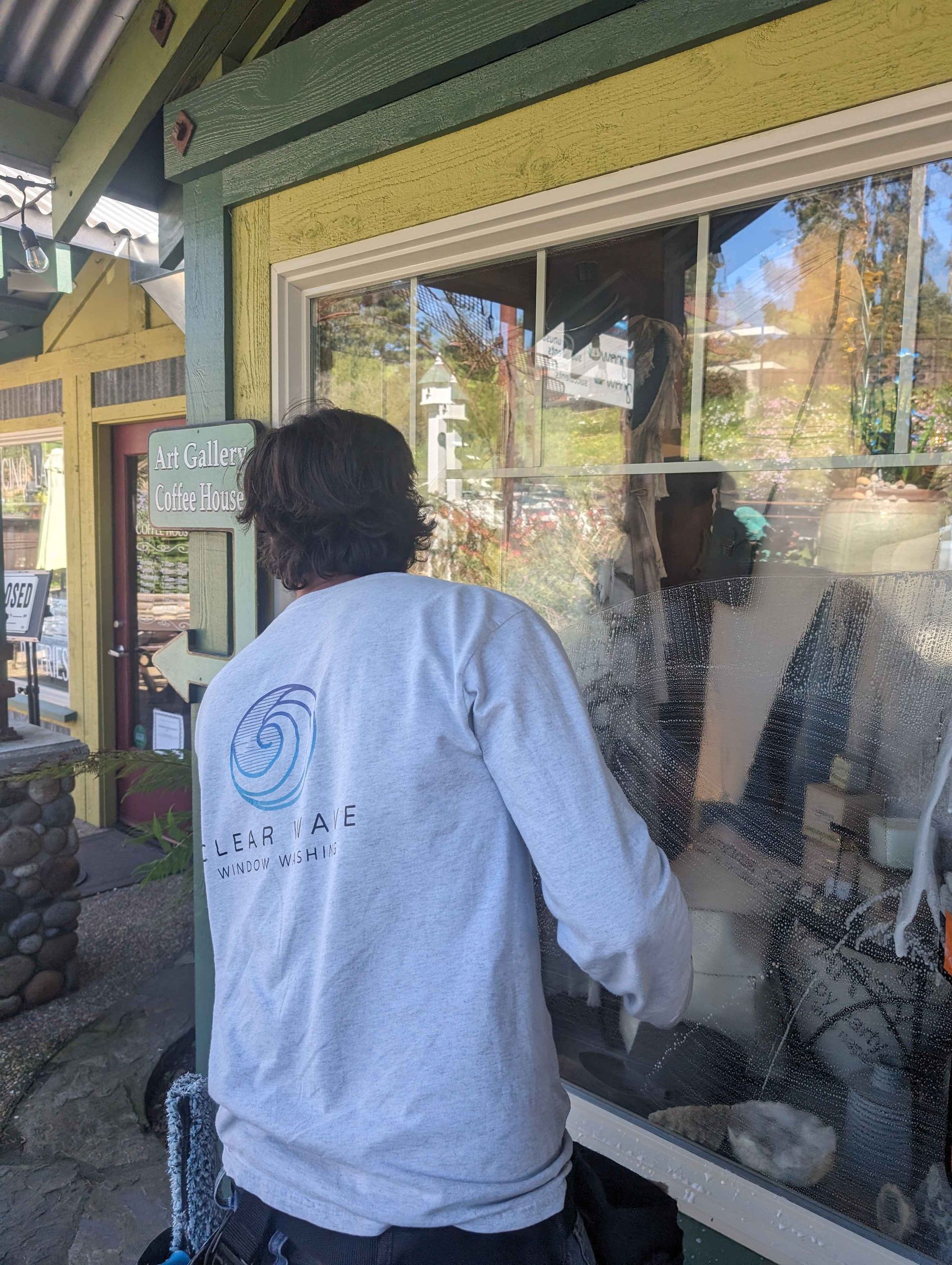 A man in a white shirt is cleaning a window.