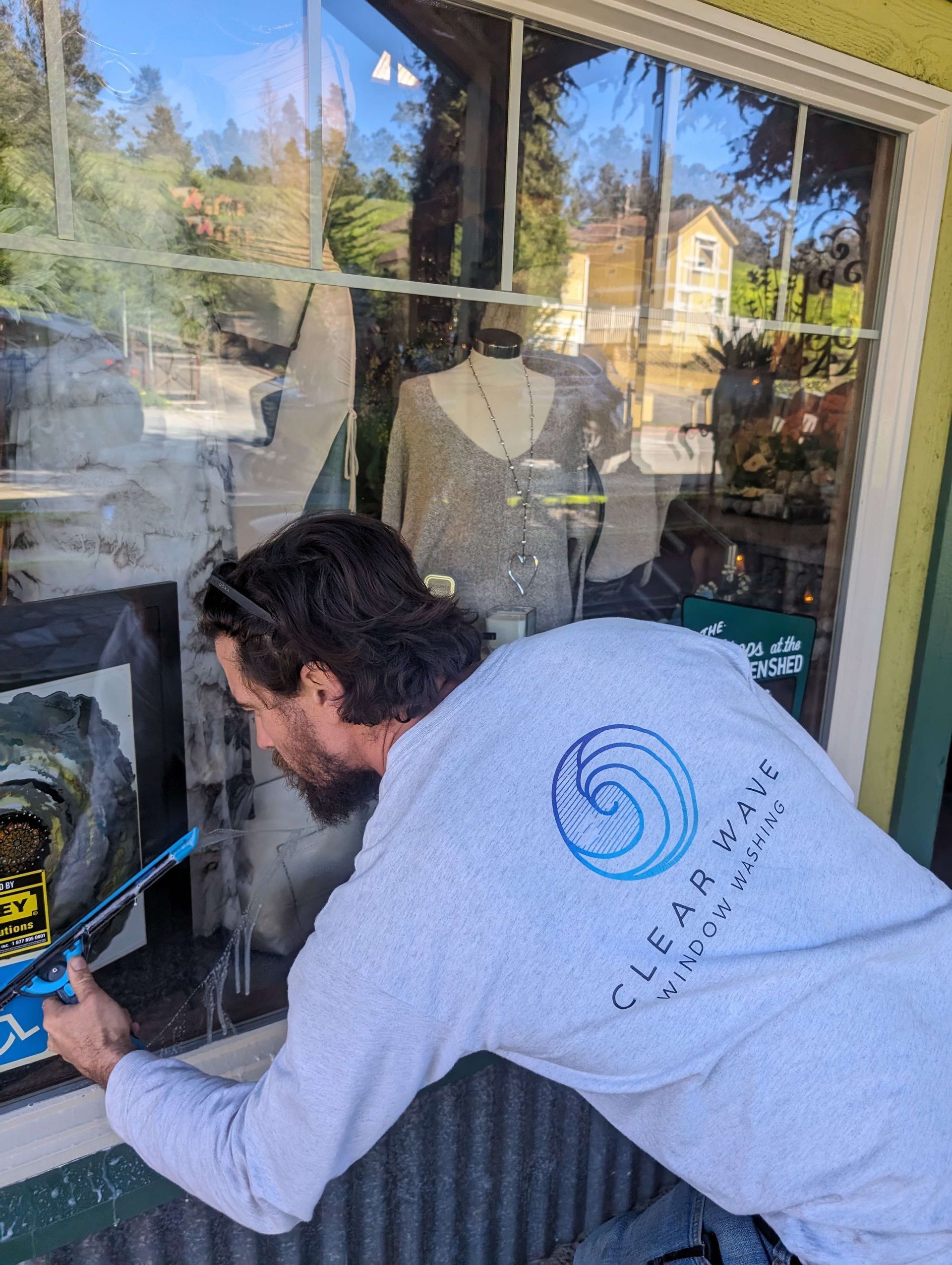 A man is cleaning a store window with a brush.