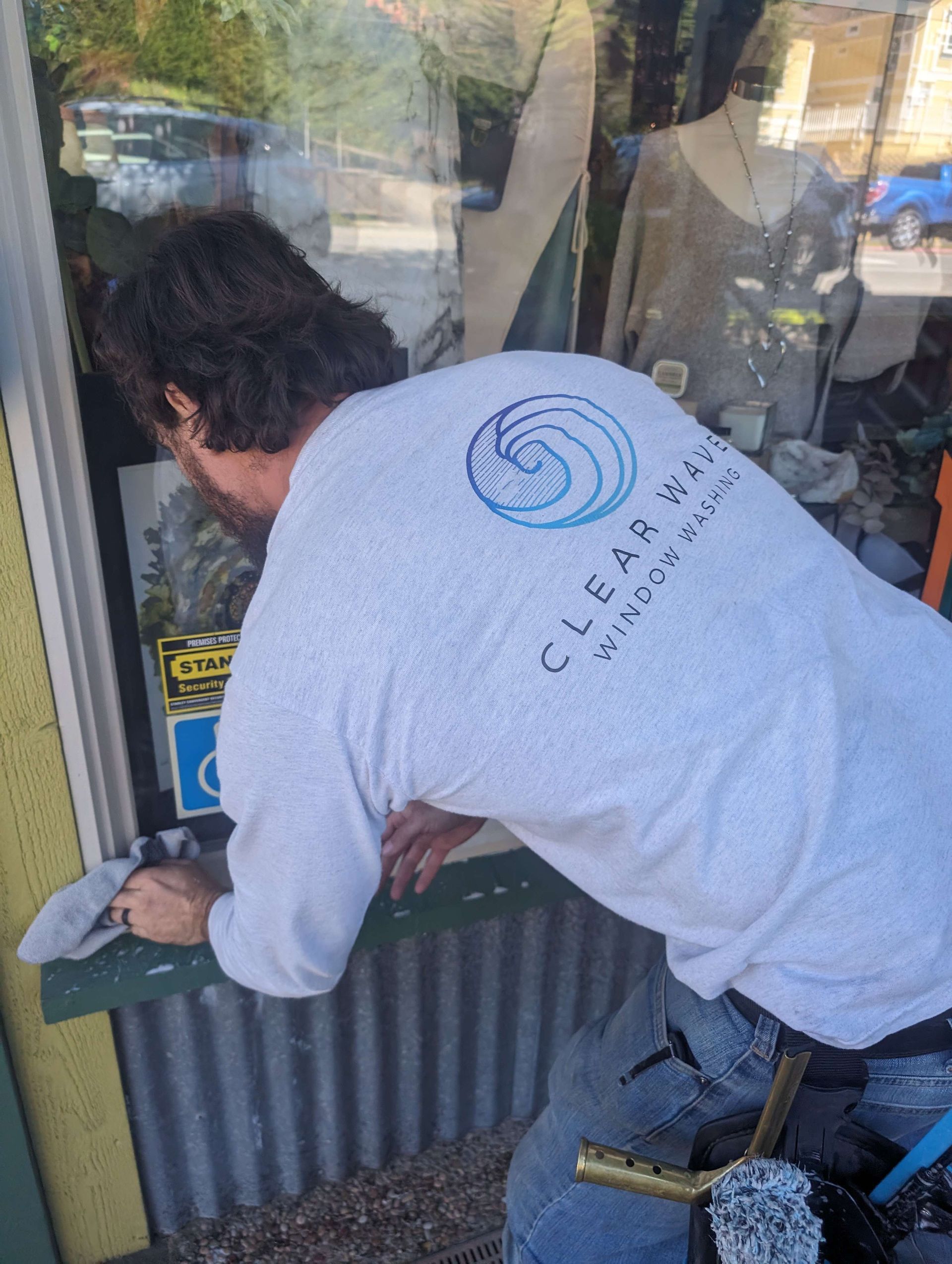 A man in a white shirt is cleaning a window.