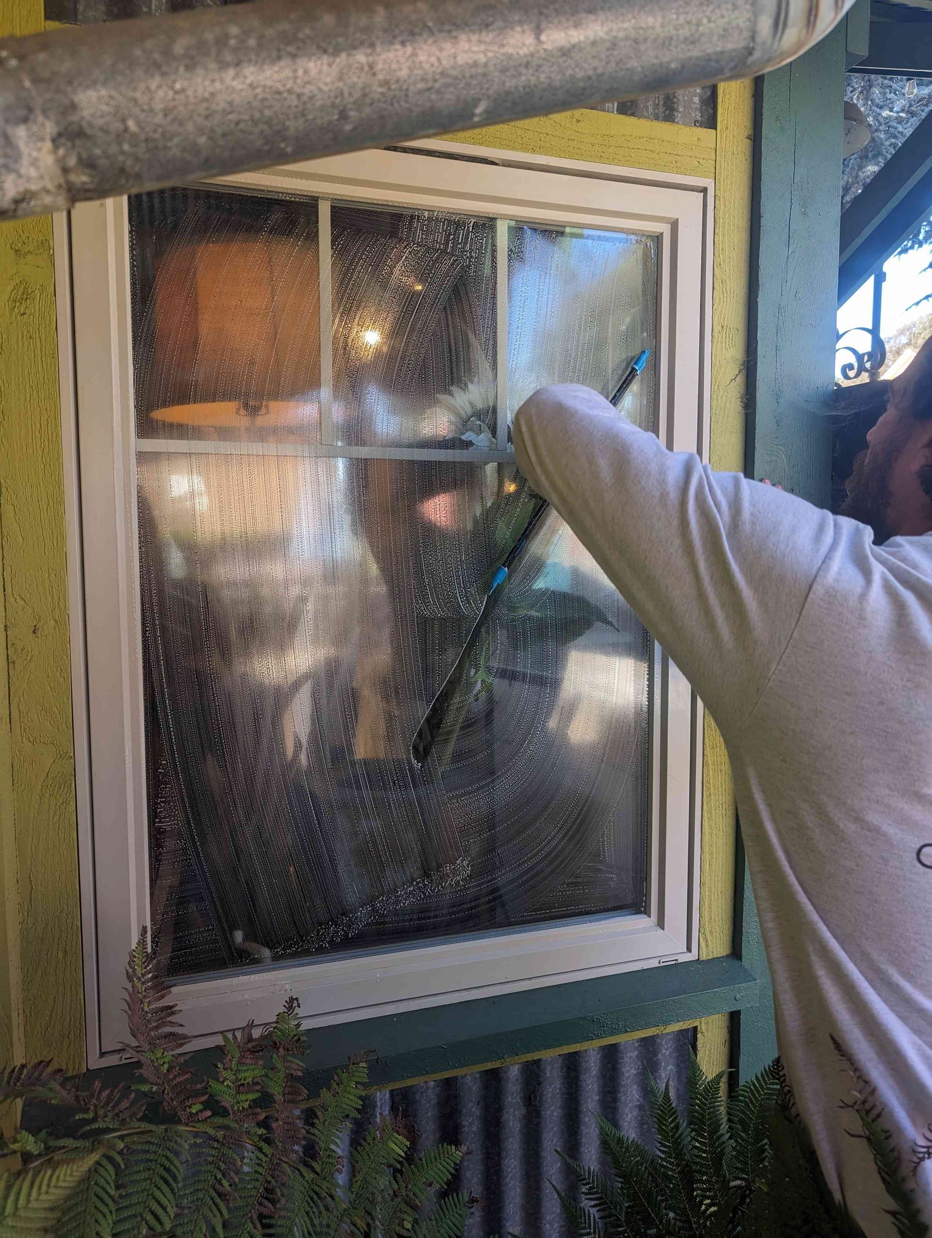 A man is cleaning a window with a brush.