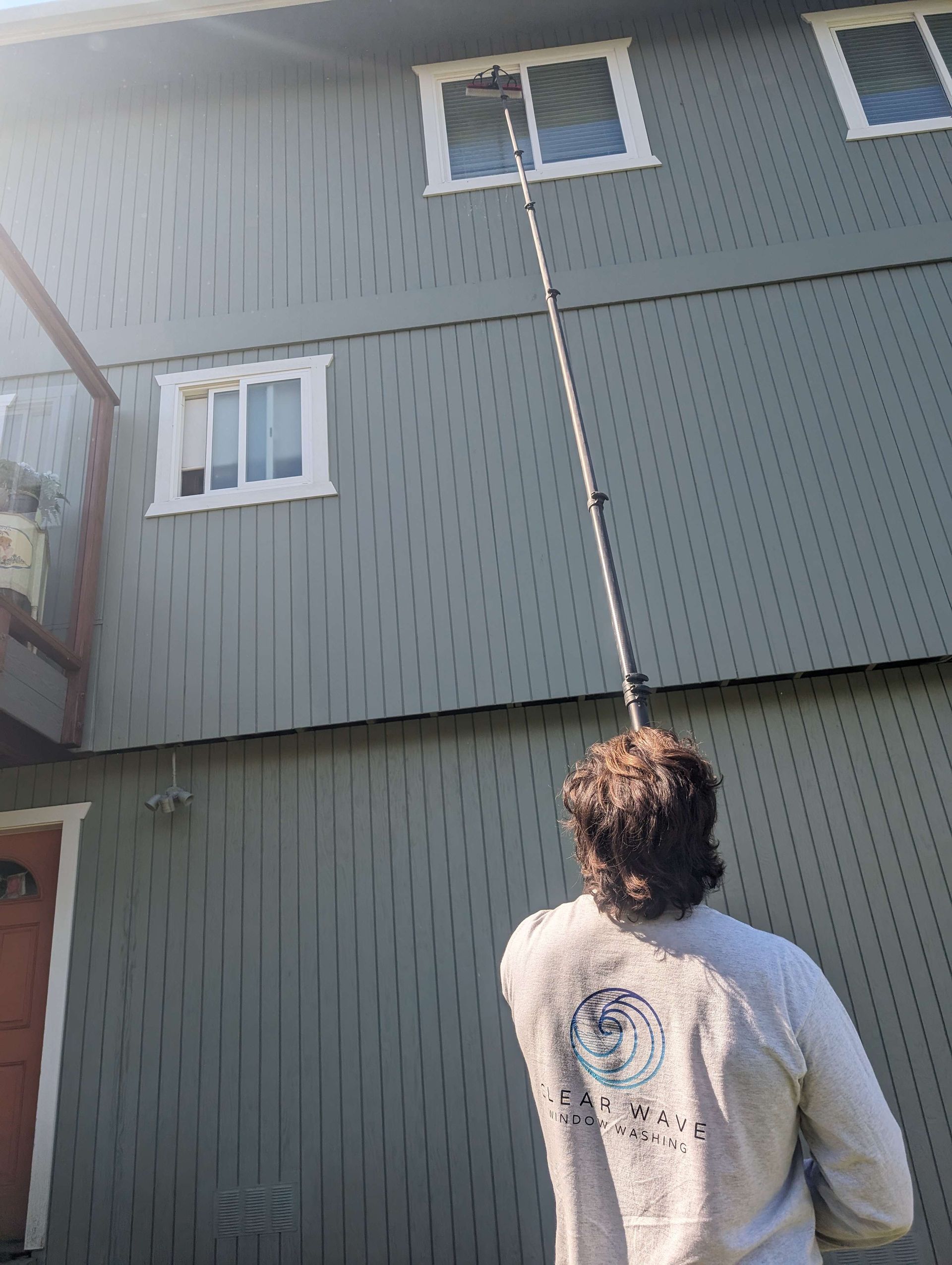 A man is cleaning the windows of a house with a high pressure washer.
