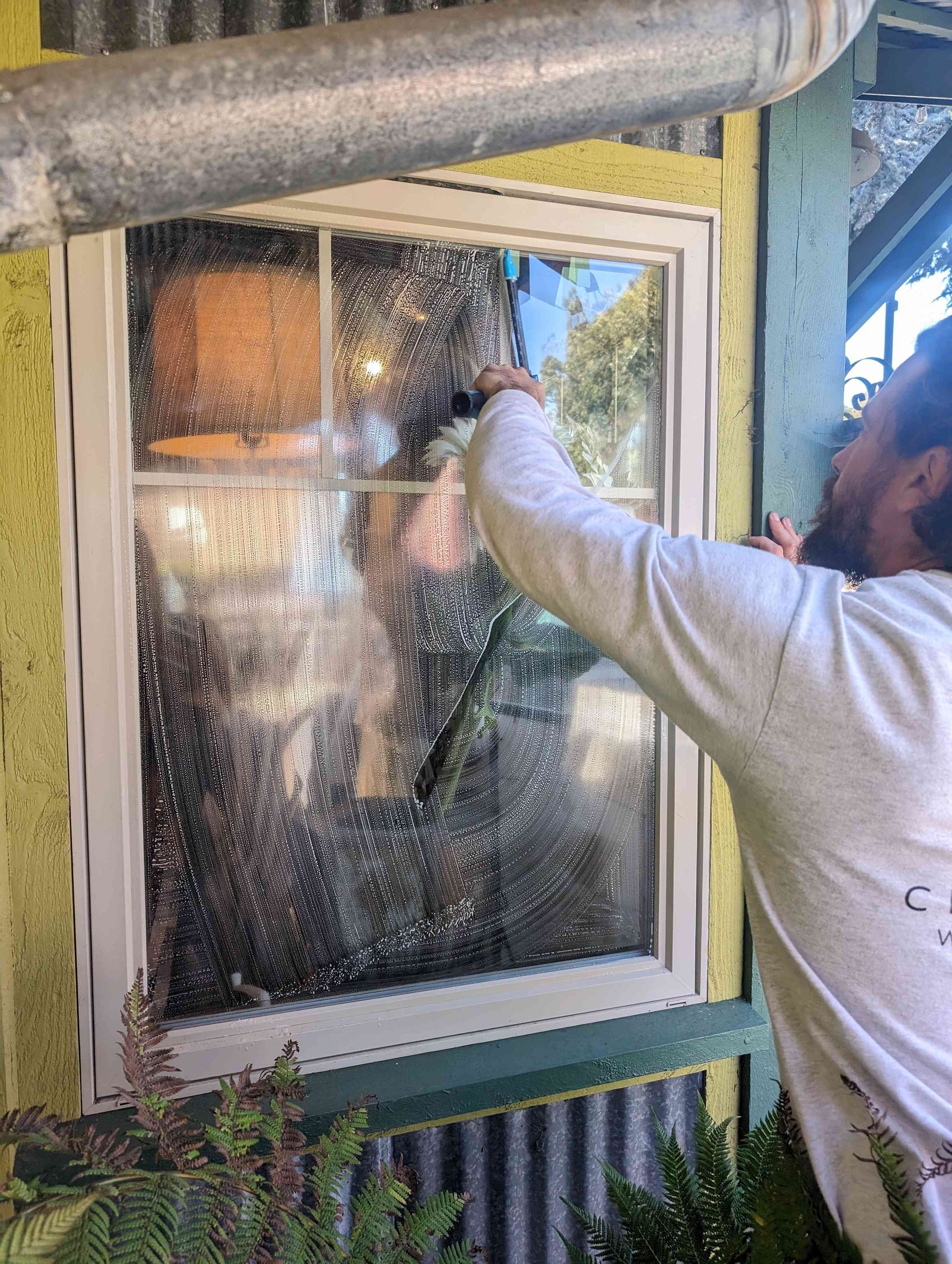 A man is cleaning a window with a brush.