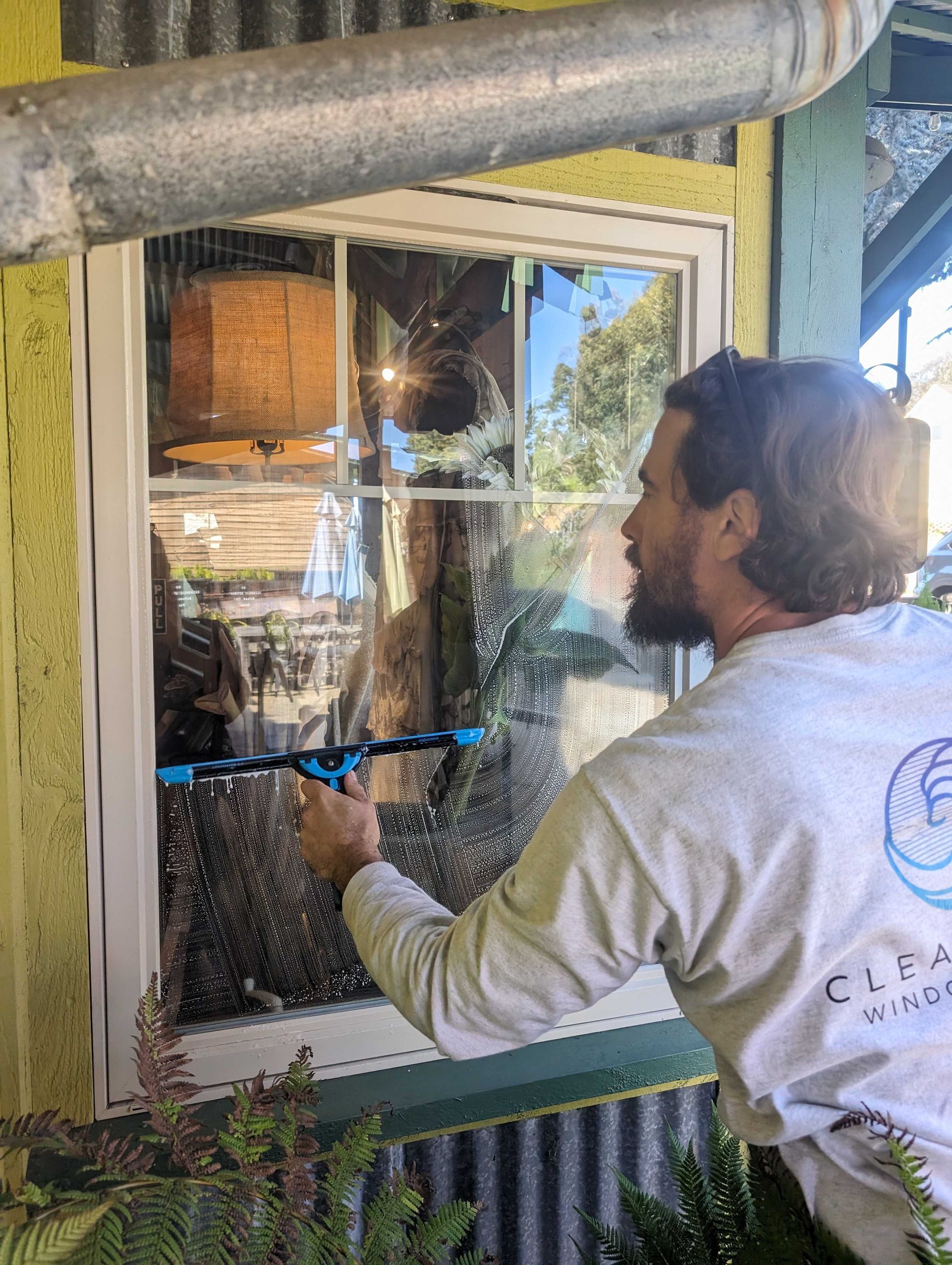 A man is cleaning a window with a spray bottle.
