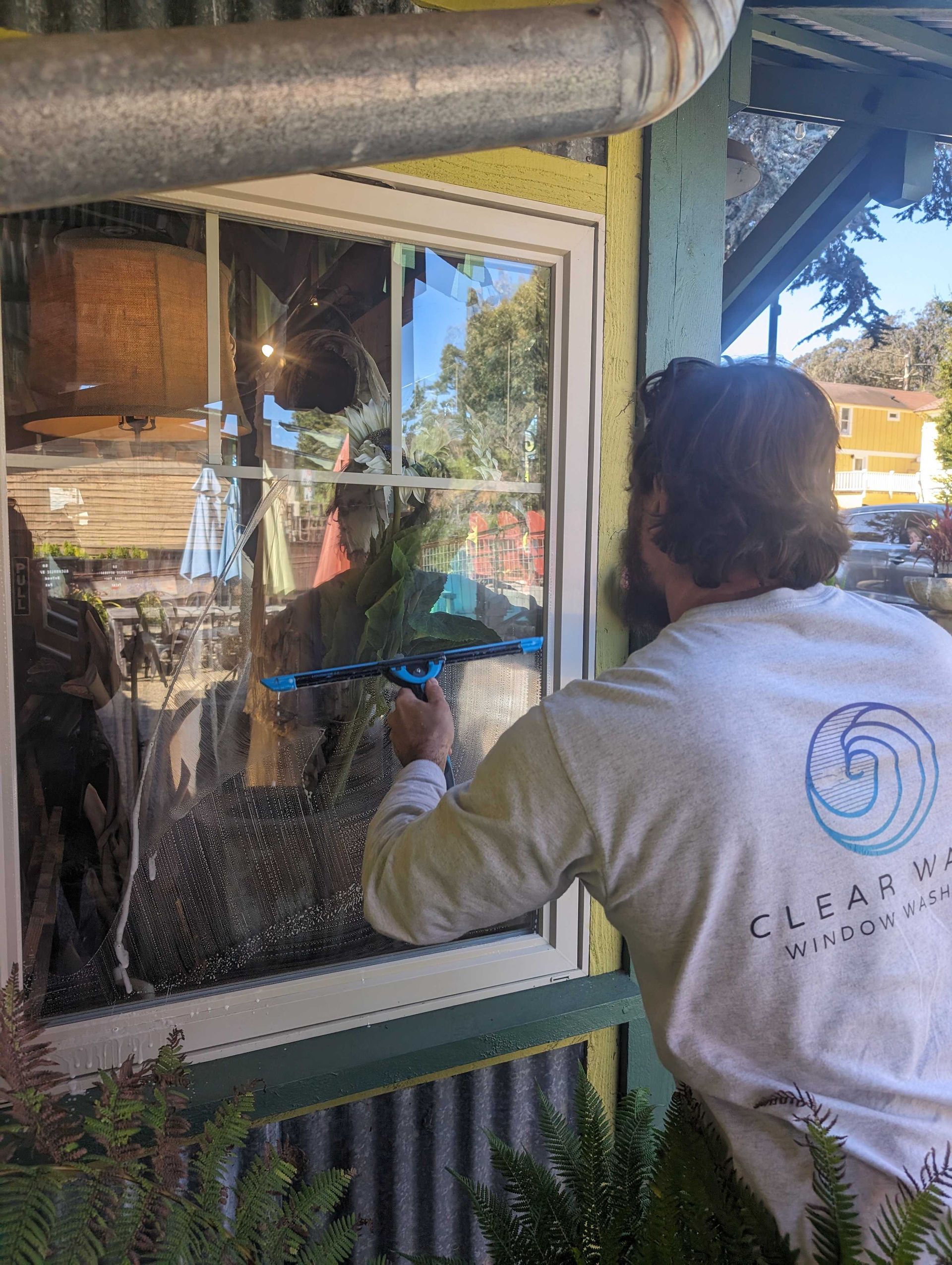 A man is cleaning a window with a squeegee.