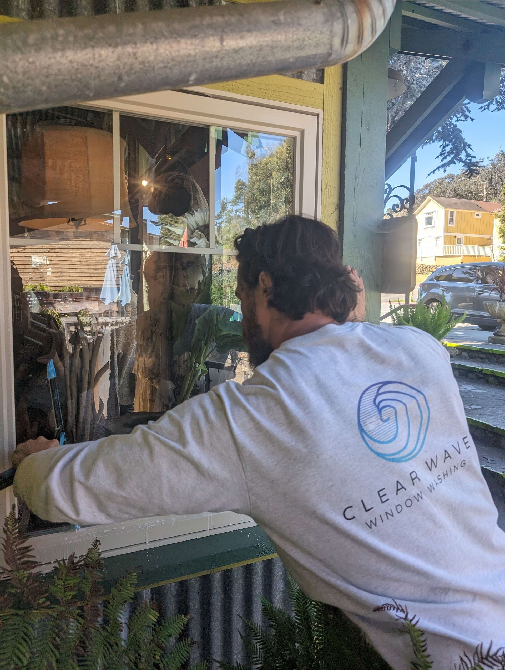 Man in a white shirt is cleaning a window.