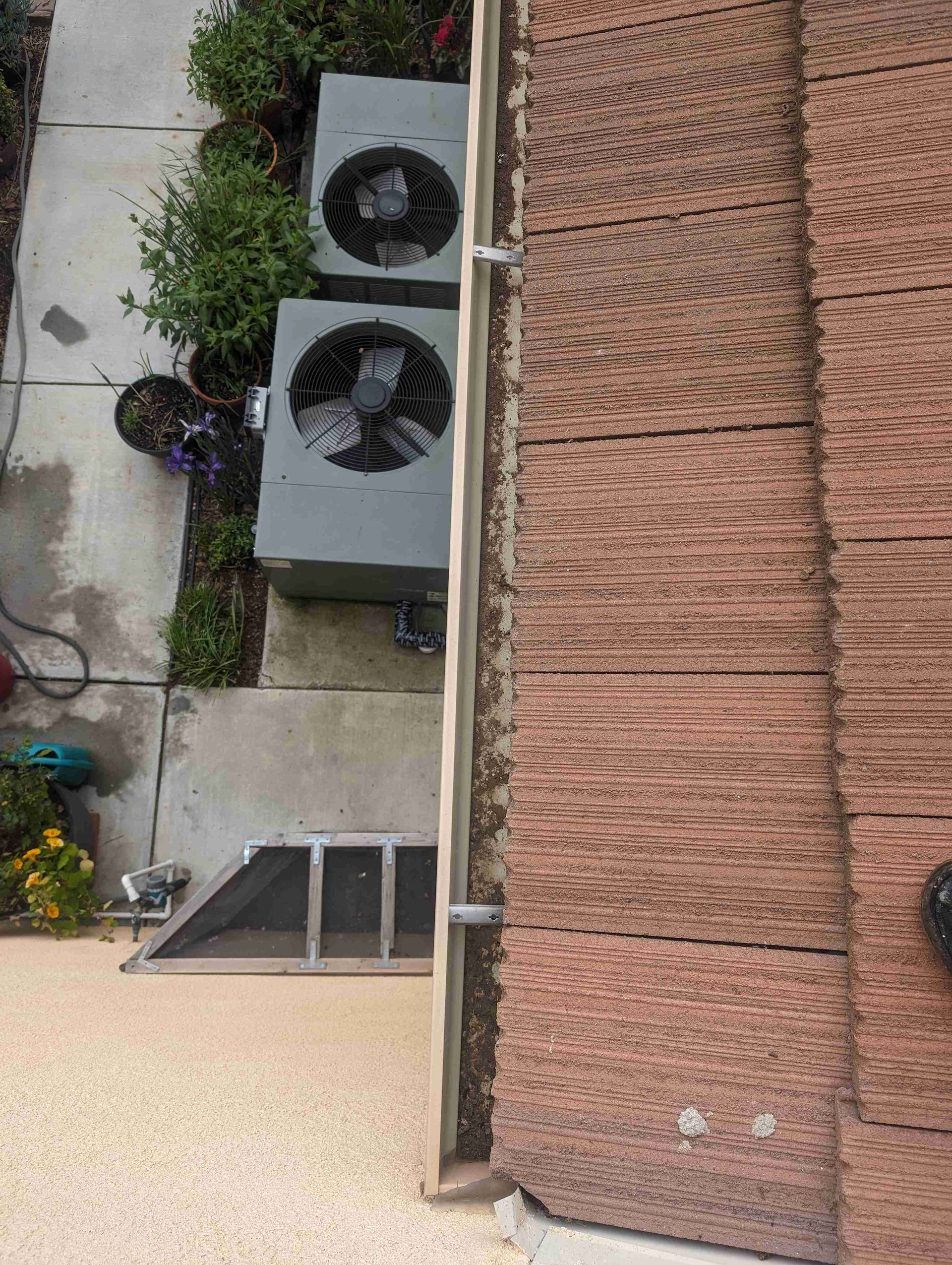 Two air conditioners are sitting on the side of a building.