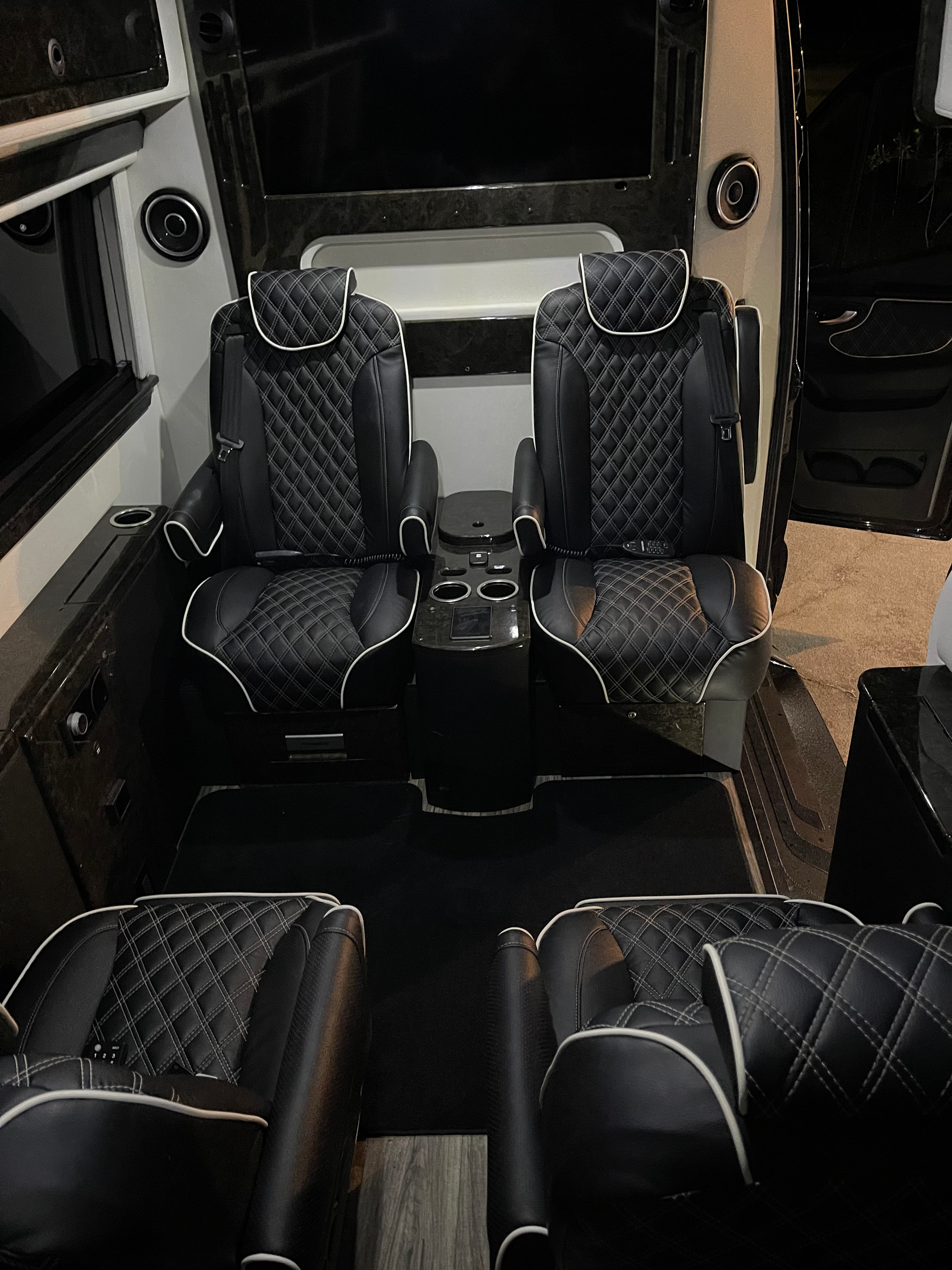 The inside of a van with two black leather seats and a table.