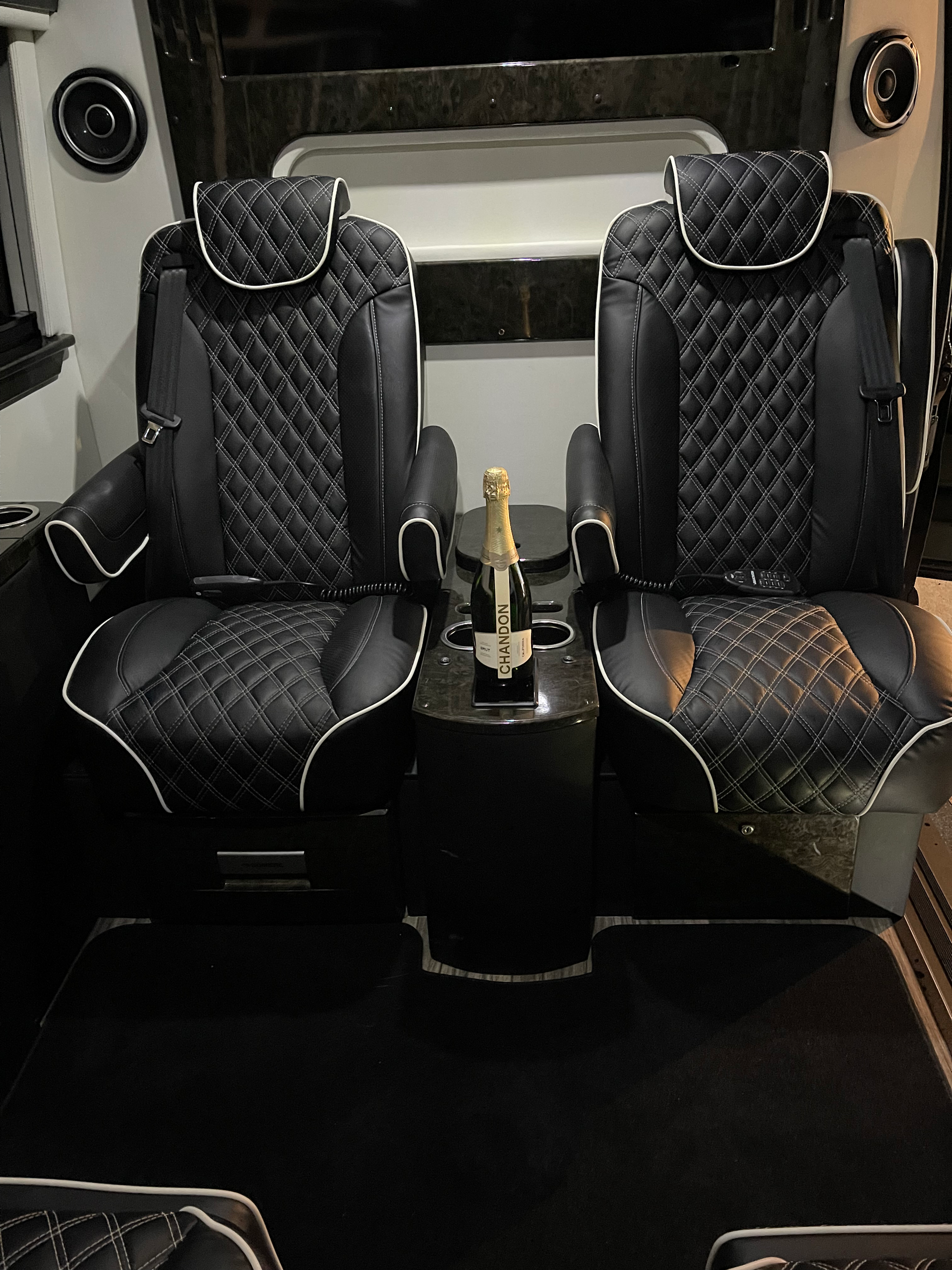 A bottle of champagne is sitting on a table between two seats in a car.