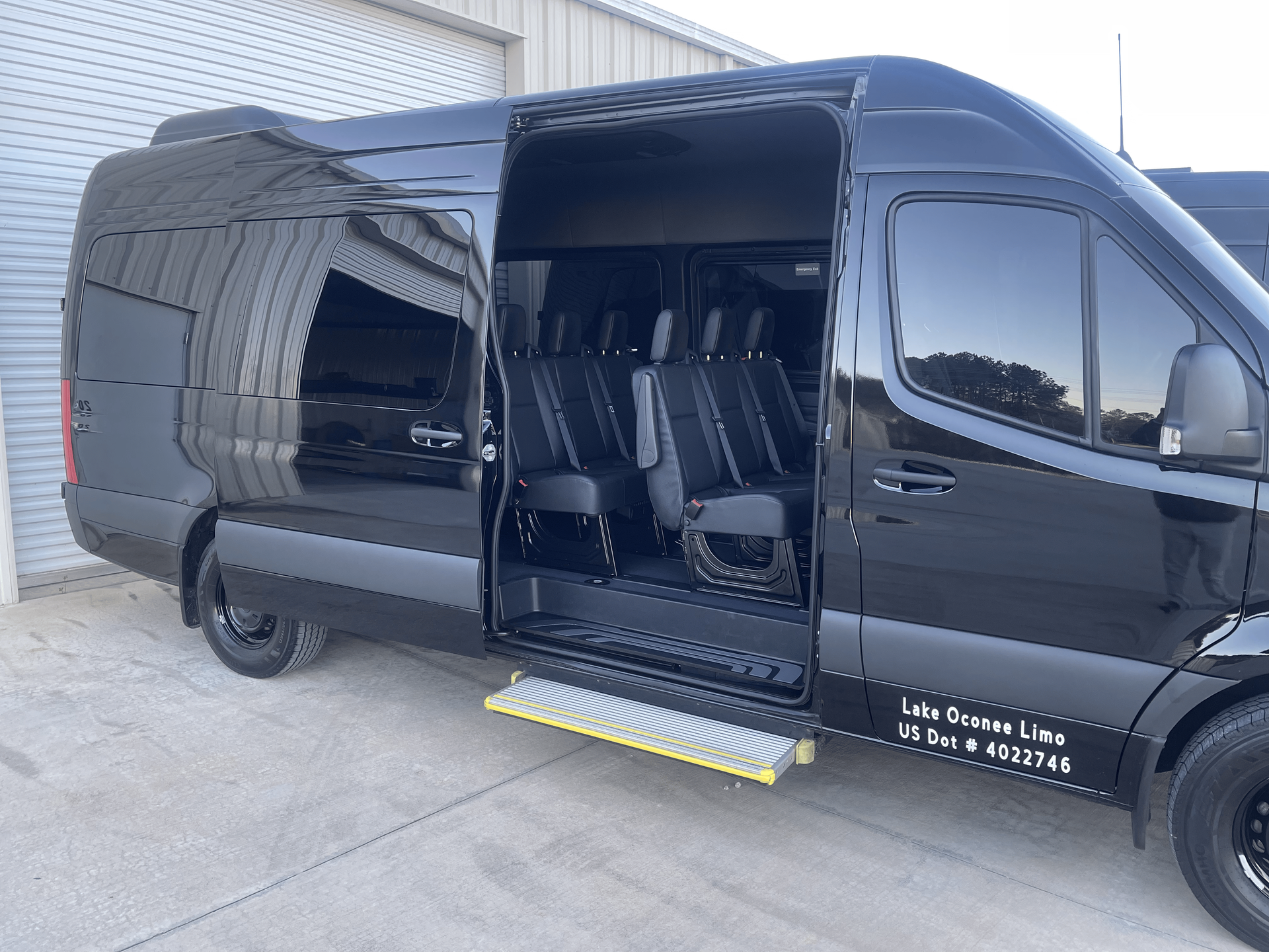 A black van with the door open is parked in front of a building.