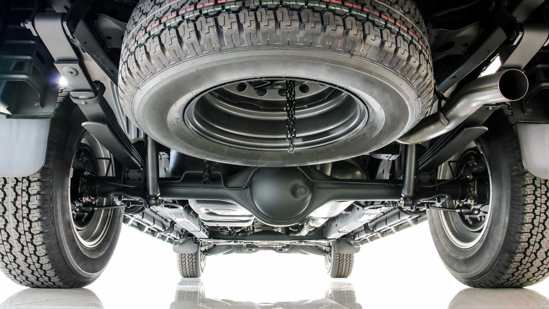 The underside of a truck with a spare tire underneath it