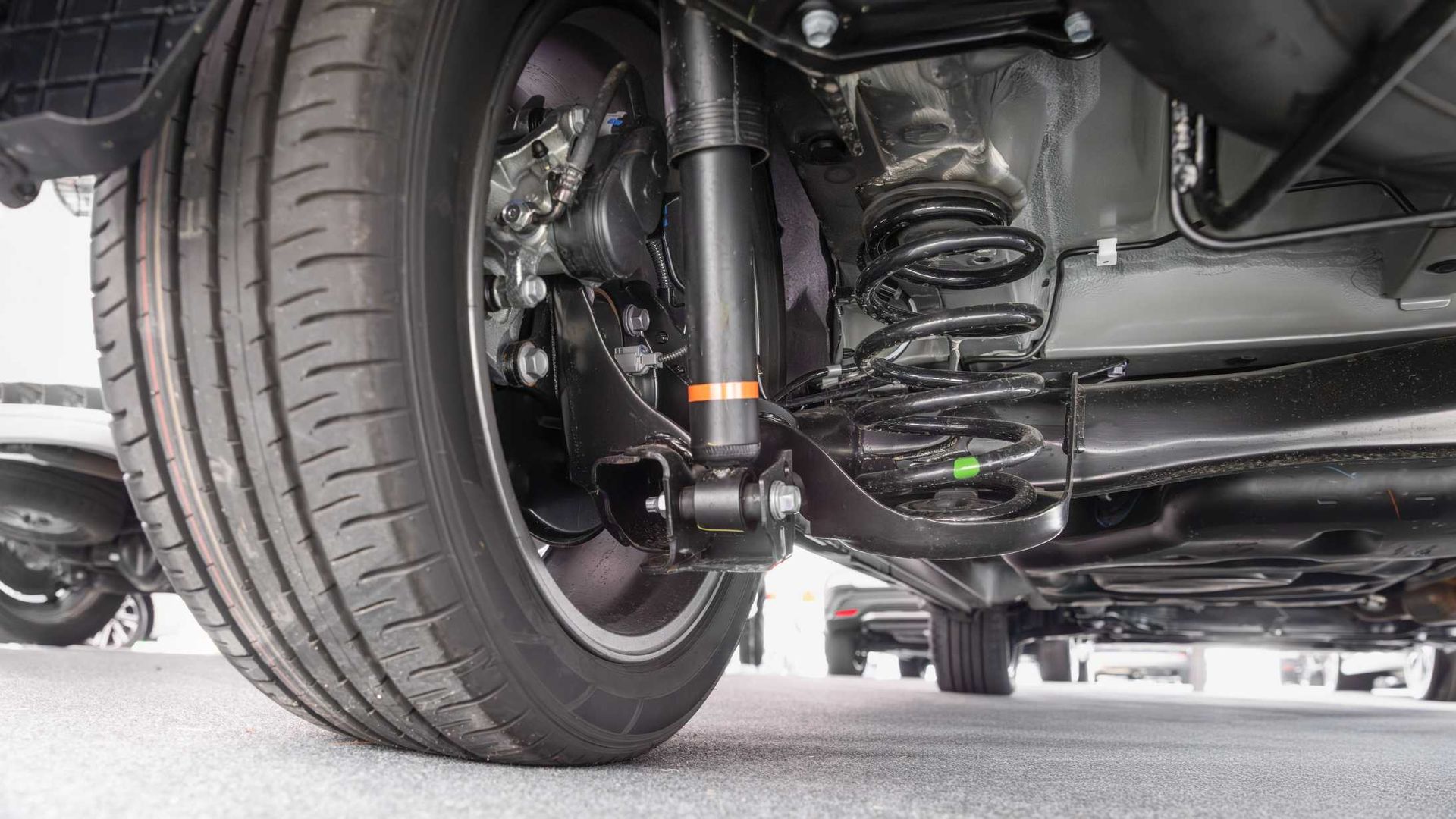 A close up of the underside of a car with a shock absorber and a tire.