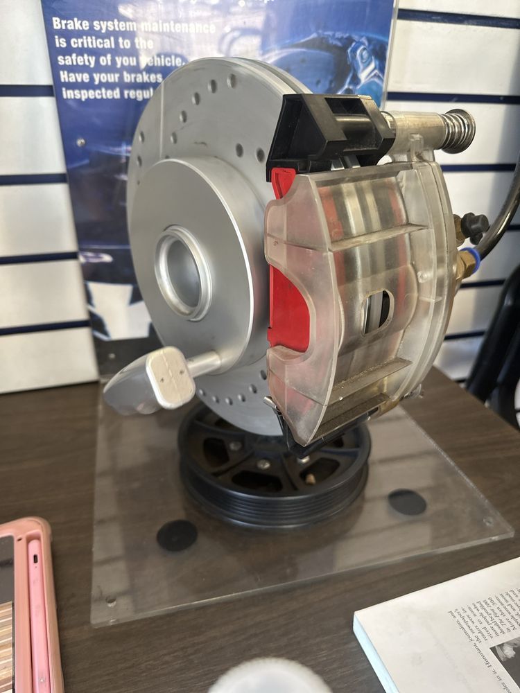 A mechanic is working on a brake disc on a car in a garage.