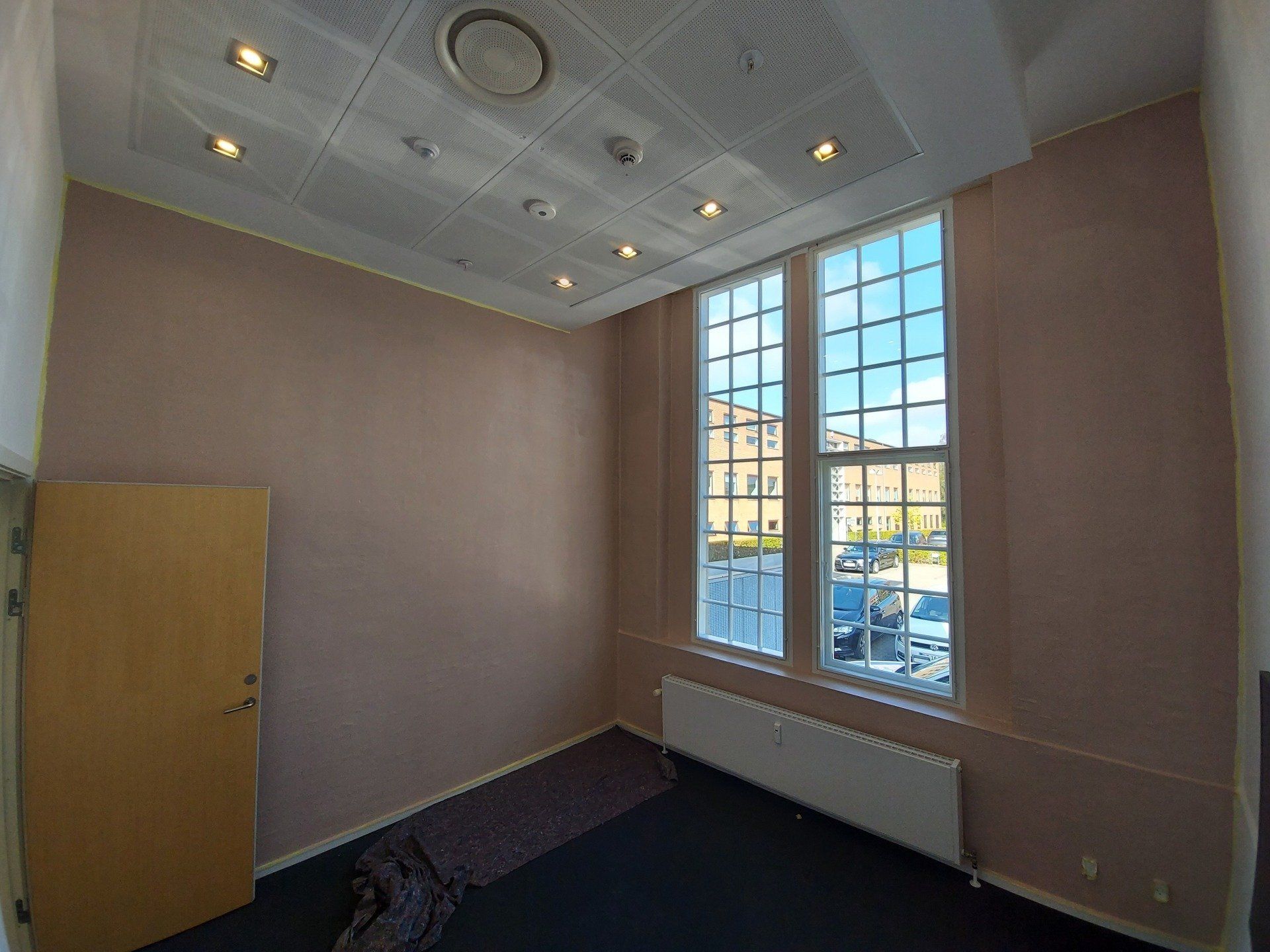 Et tomt rum med to vinduer og en dør.