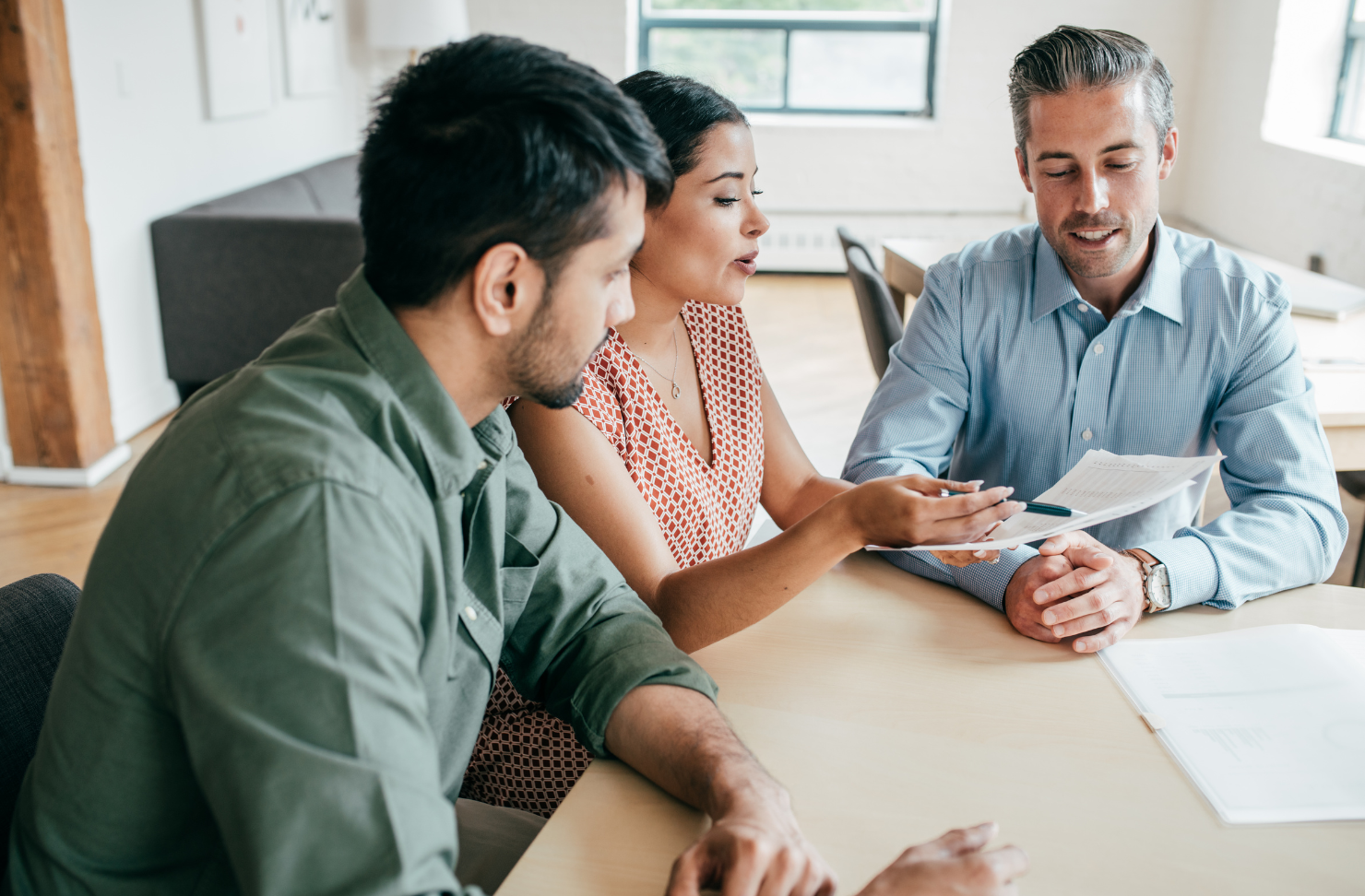A man and a woman are sitting at a table talking to a real estate agent.