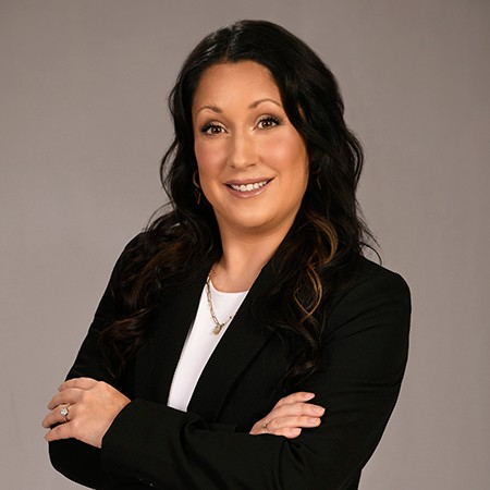 A woman wearing a green and white checkered shirt is smiling.