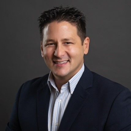 A man in a suit and striped shirt is smiling for the camera.