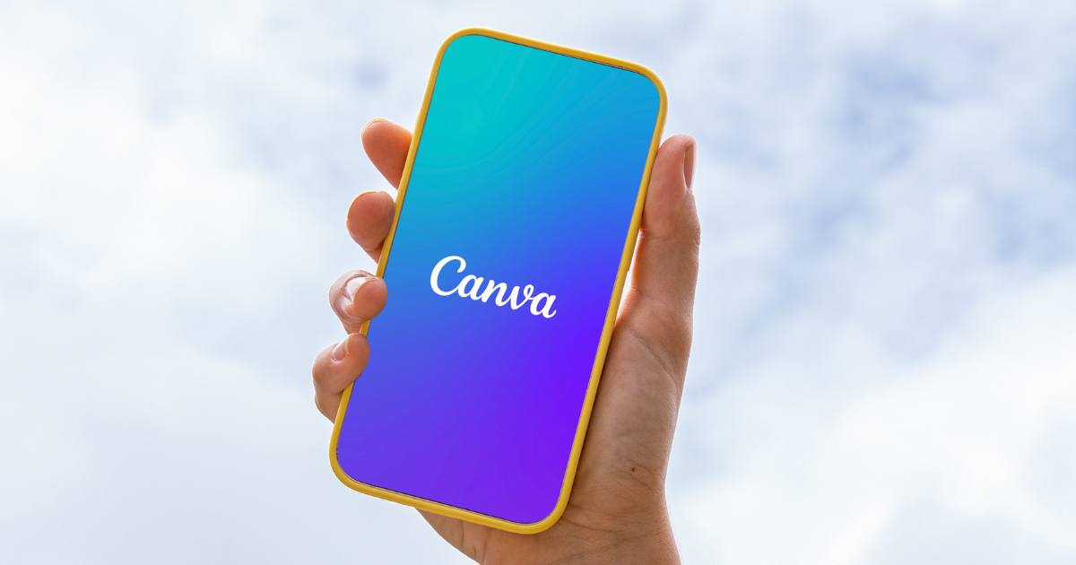 Hand holding a phone with the Canva logo, against a blue and white sky.