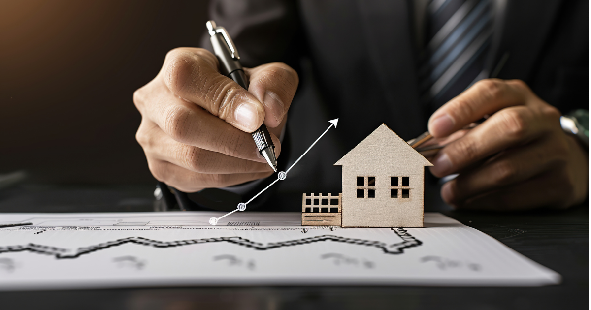 Person in suit drawing upward trend line over a house model on a graph.
