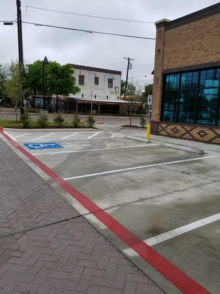Parking lot with accessible parking space, building with large windows, brick walkway.