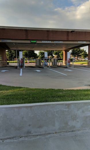 Drive-thru bank teller lanes under a brick overhang; white arrows indicate traffic flow.
