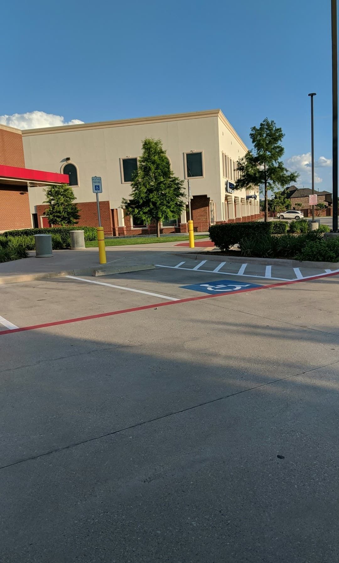 Parking lot with handicap spaces in front of a light-colored building under a blue sky.