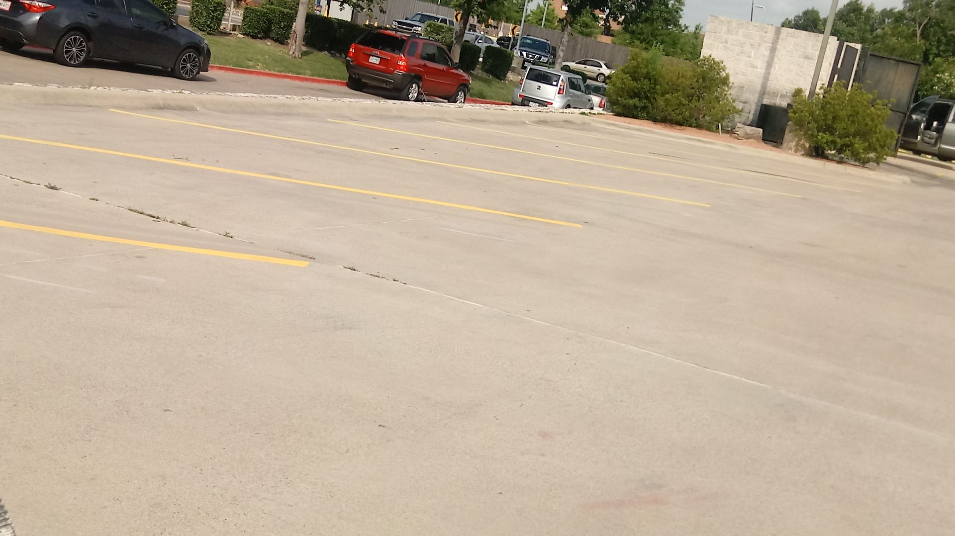 Parking lot with several cars parked. Red and black cars visible.
