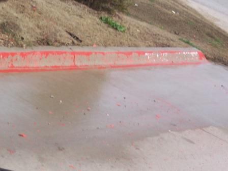Red-painted curb and concrete surface, near brown grass and pavement.