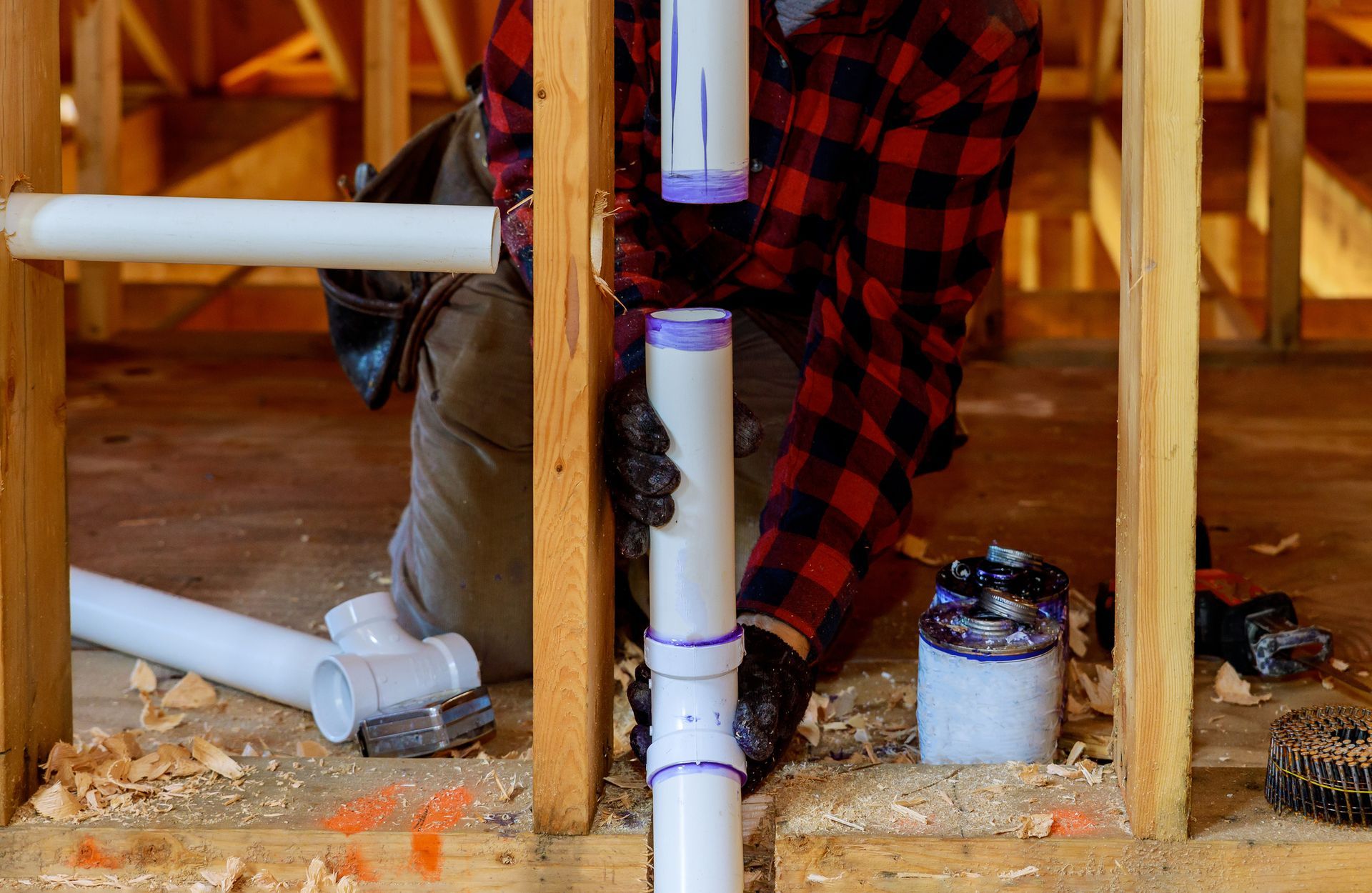 A man is installing pipes in a house under construction.