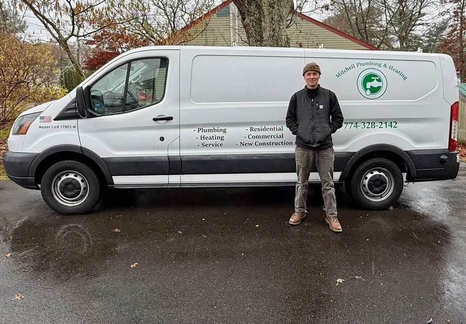 A person standing outside in front of a white Ford Transit work van with plumbing business branding on the side.