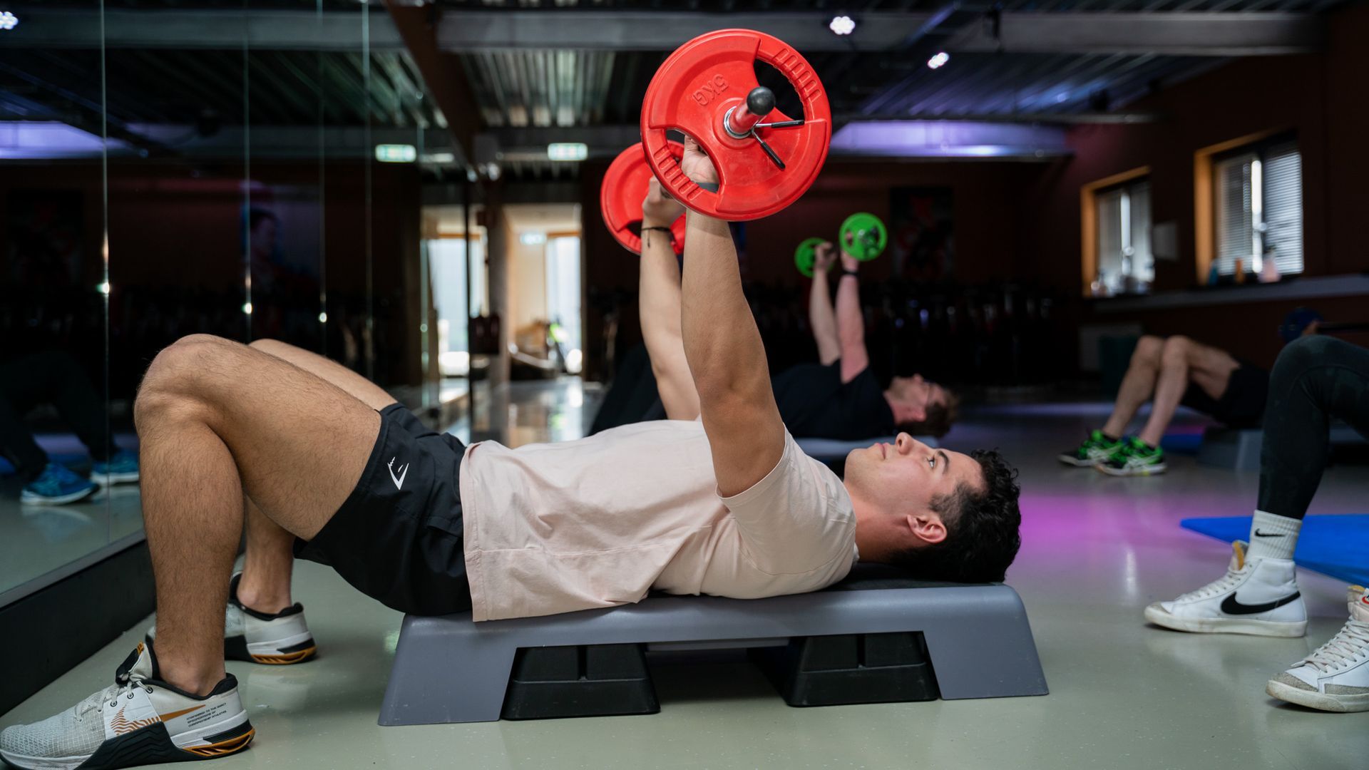 Een man tilt een halter op een bank in een sportschool.
