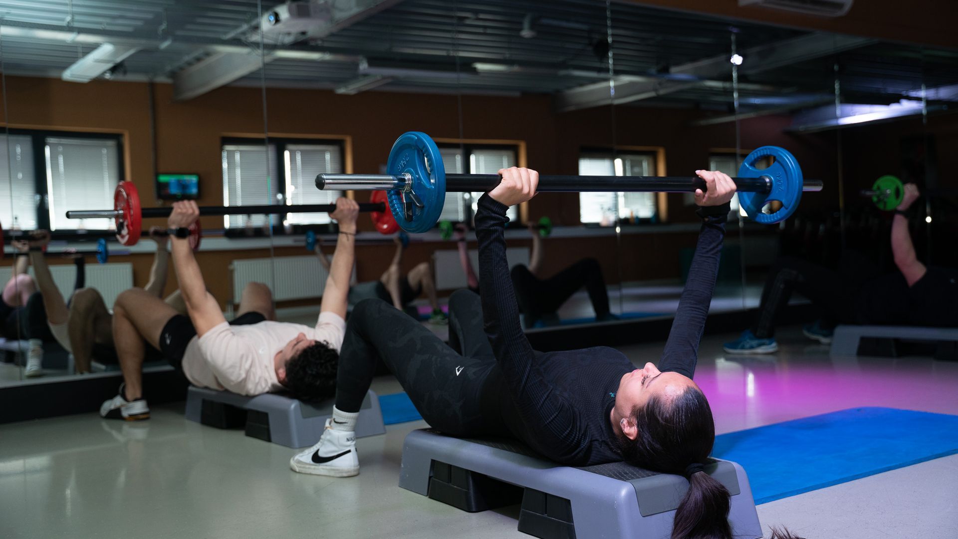 Een groep mensen is aan het gewichtheffen in een sportschool.