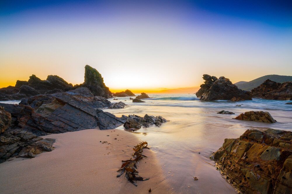 A Beach With Rocks And A Sunset In The Background — Twin Towns Removals Mid North Coast In Forster, NSW
