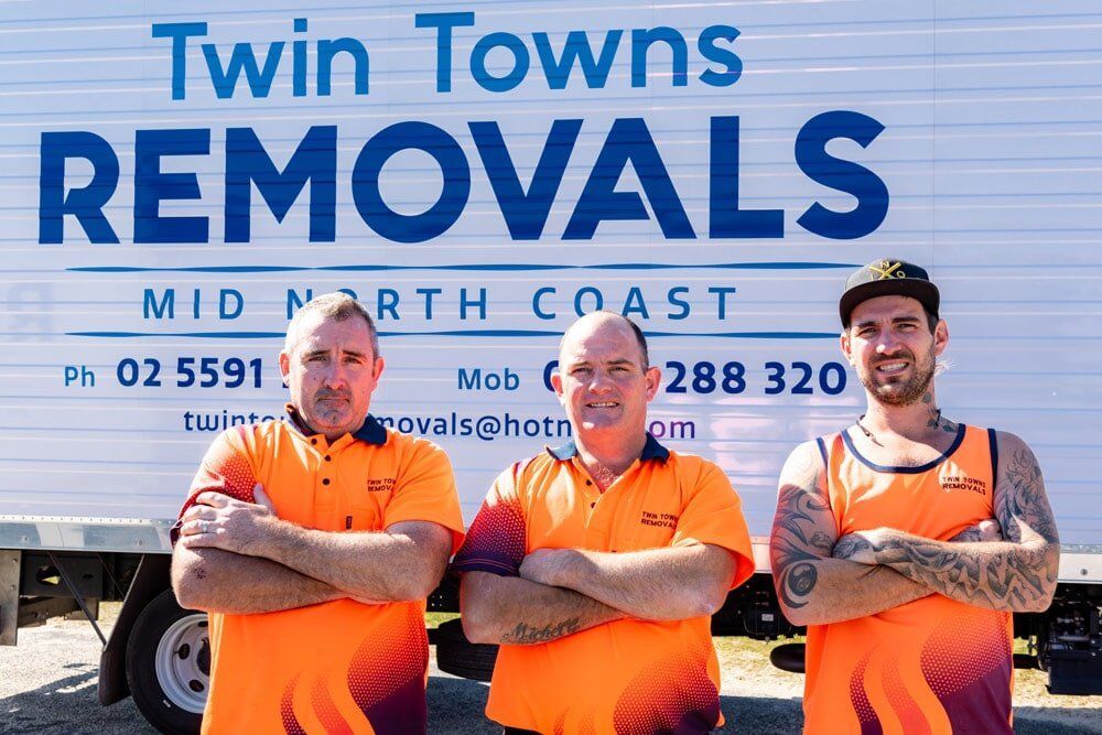 Three Men Are Standing In Front Of A Truck That — Twin Towns Removals Mid North Coast In Tuncurry, NSW