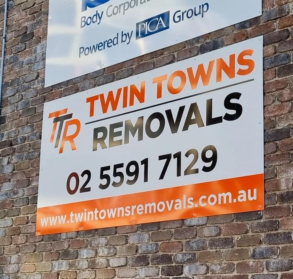 A Sign For Twin Towns Removals Hangs On A Brick Wall — Twin Towns Removals Mid North Coast In Tuncurry, NSW