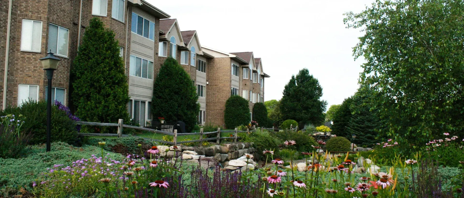 A large apartment building with a lot of flowers in front of it