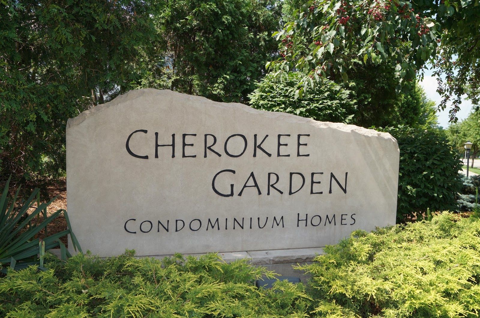 A large stone sign for cherokee garden condominium homes