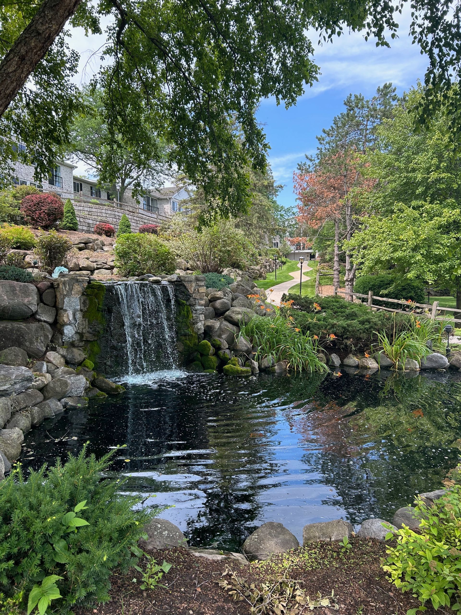 There is a waterfall in the middle of a park surrounded by trees.