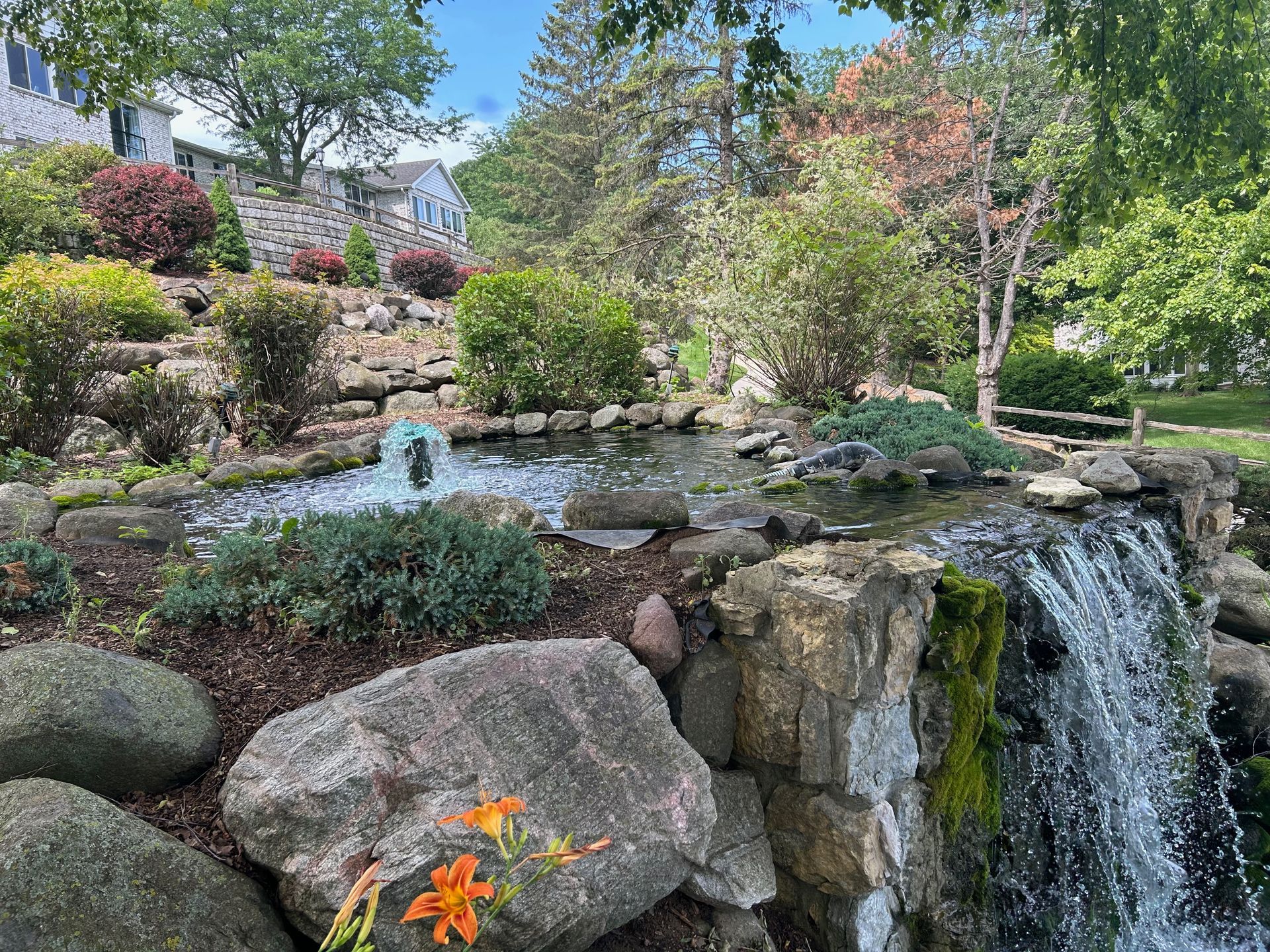 A waterfall is surrounded by rocks and trees in a park.
