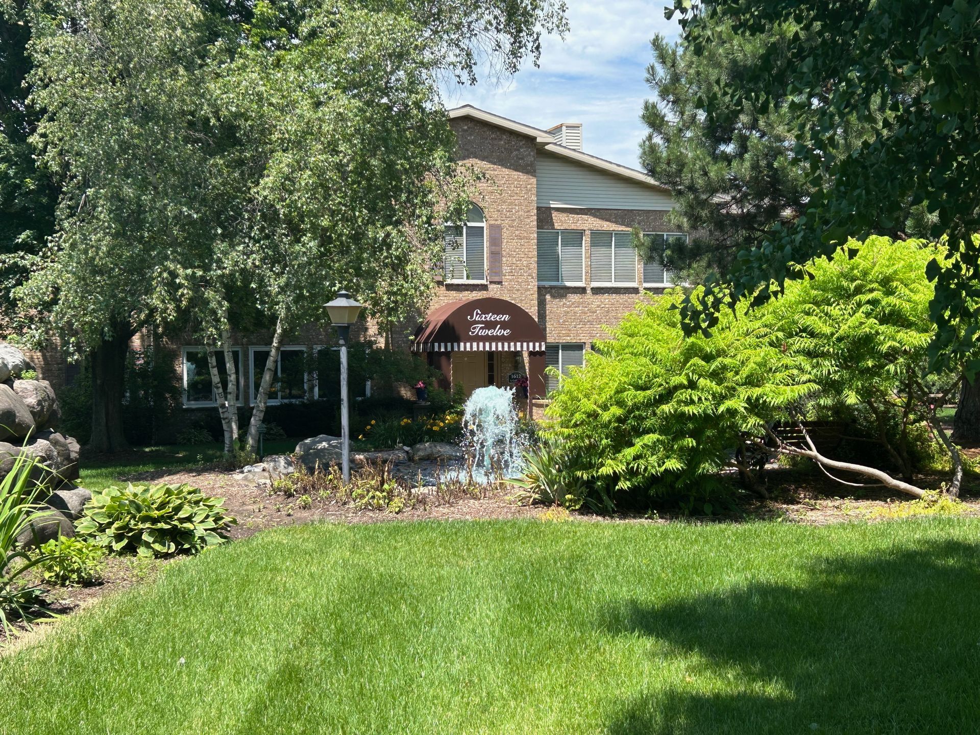 A large brick house with a fountain in front of it