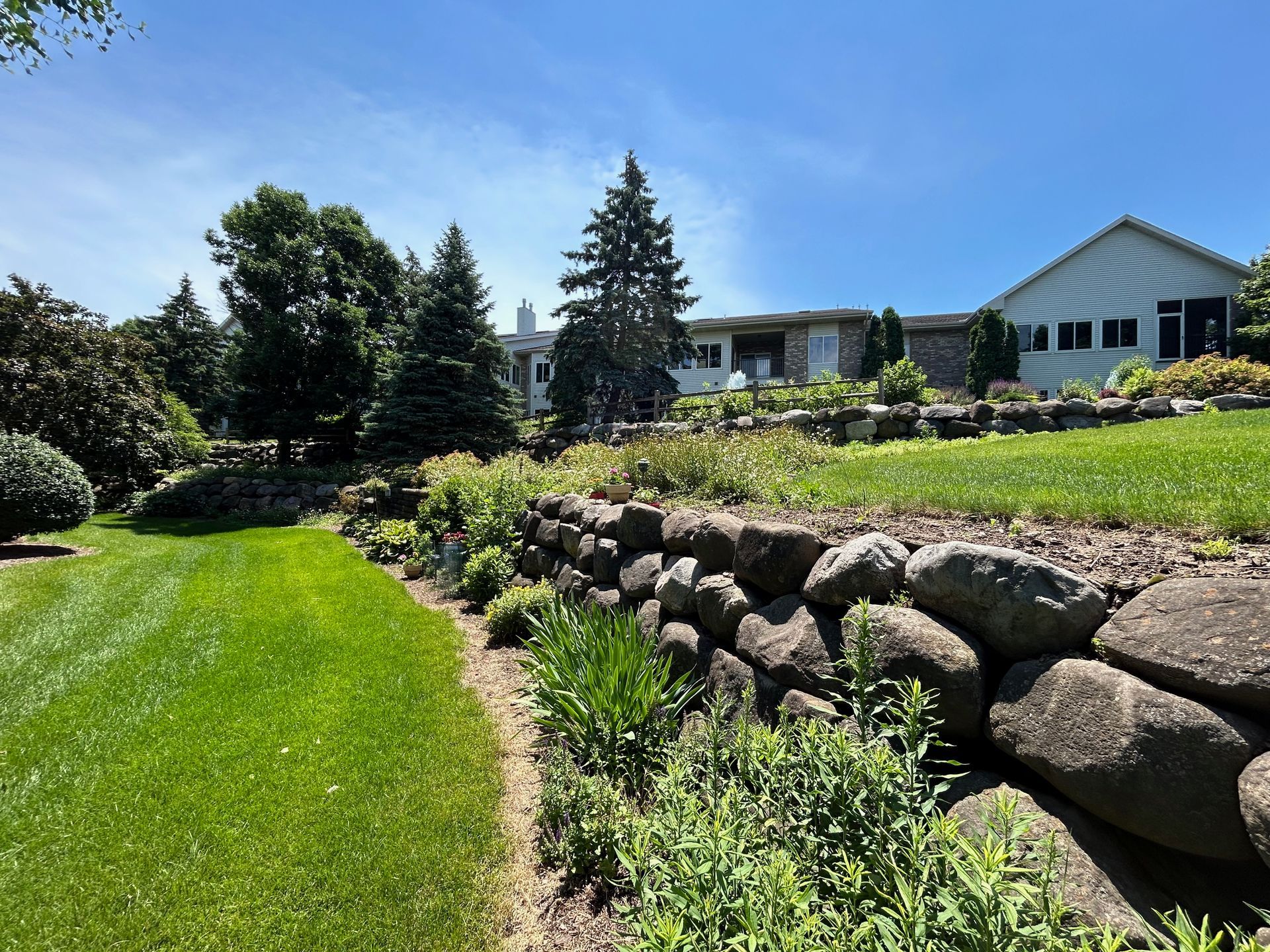 There is a large house in the background and a rock wall in the foreground.
