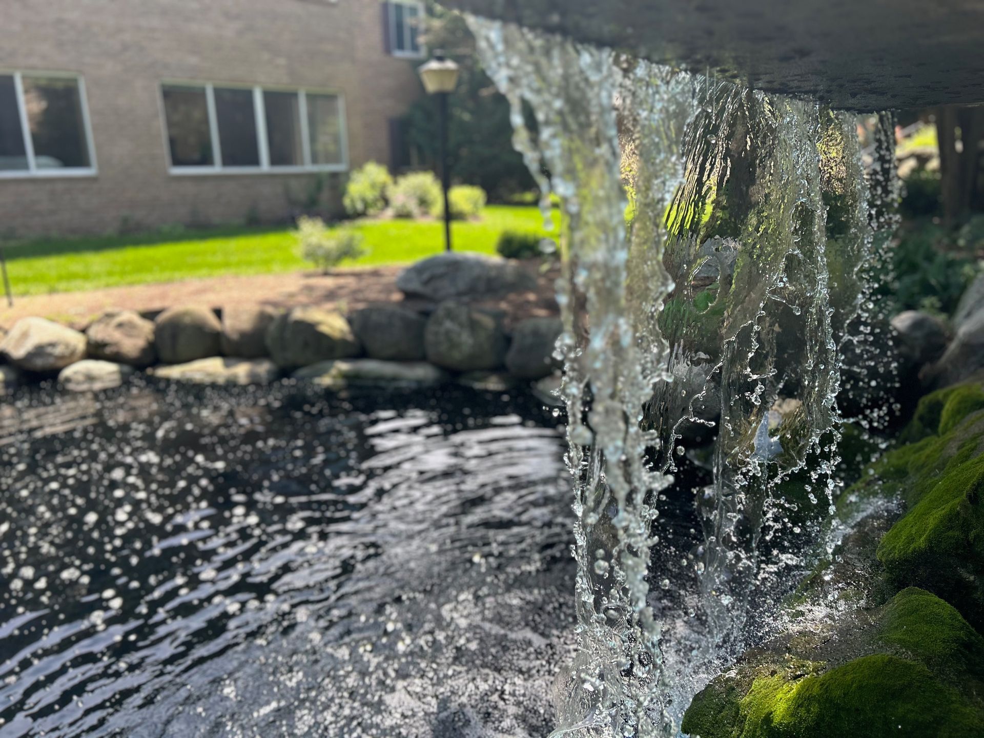A waterfall is falling into a pond in front of a building.