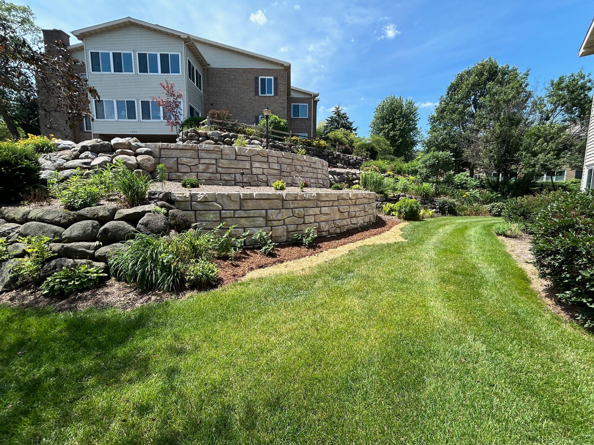 A large house is sitting on top of a hill next to a lush green lawn.