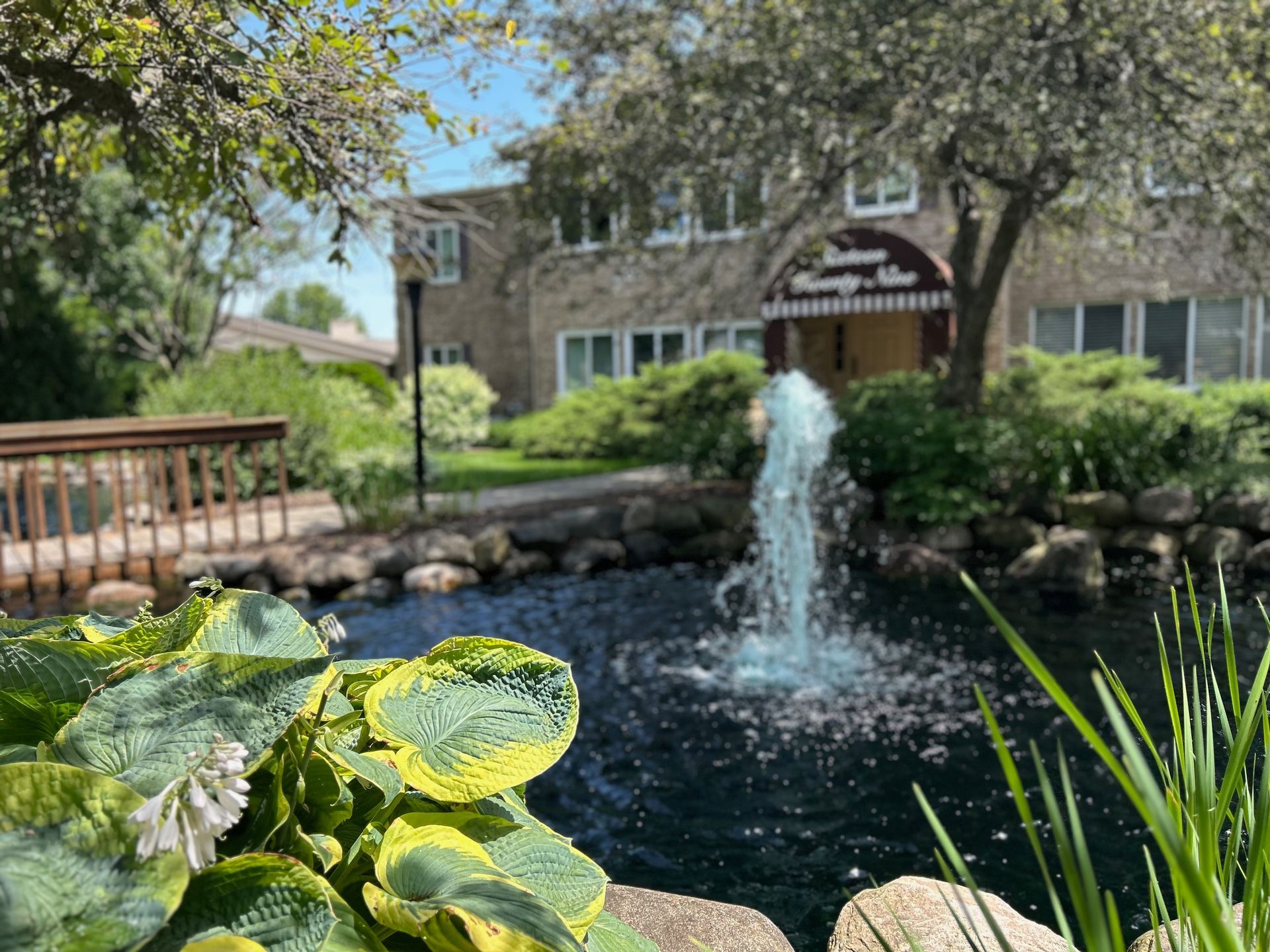 There is a fountain in the middle of a pond in front of a building.