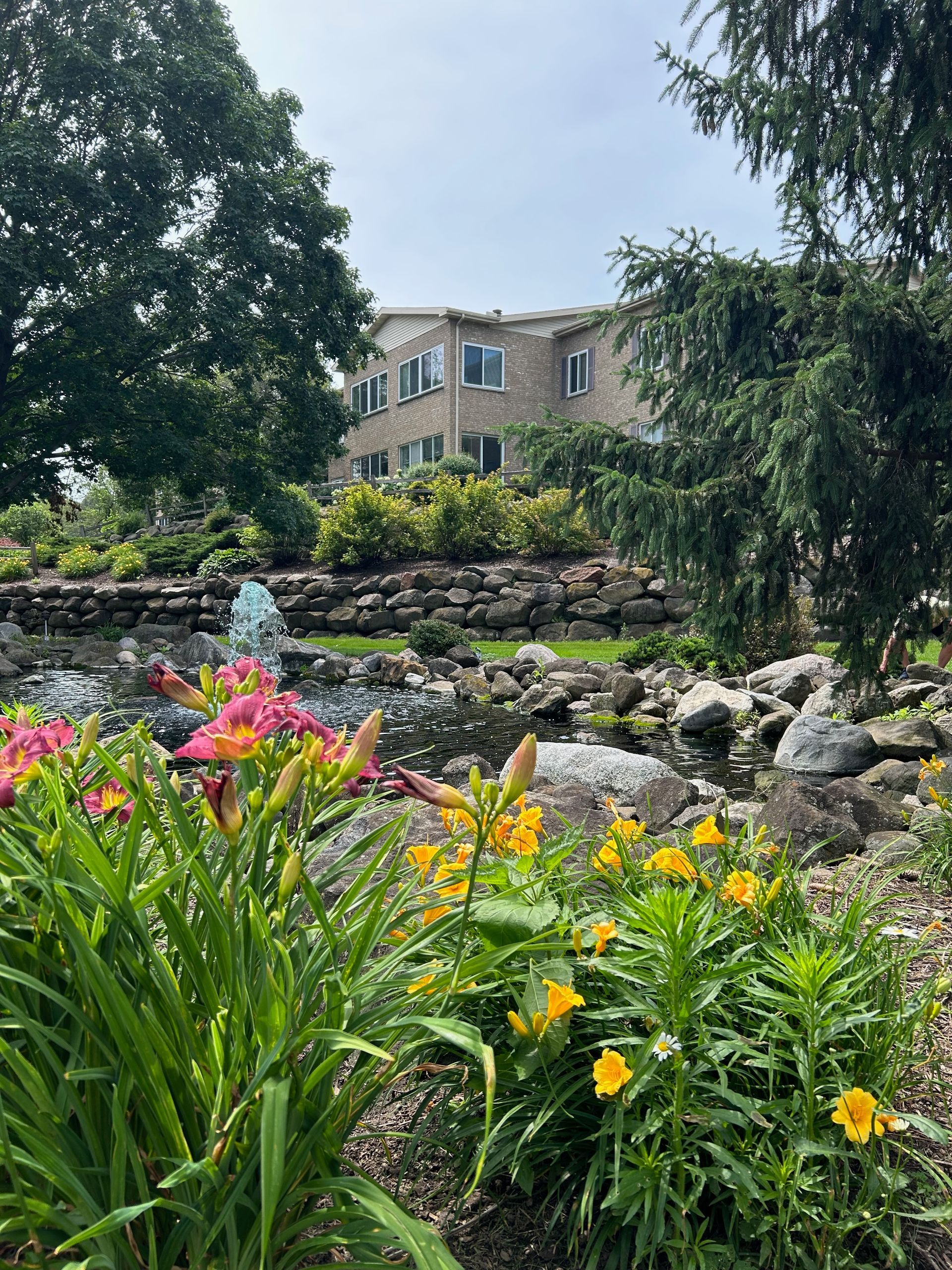 A garden with flowers and a fountain in front of a house.