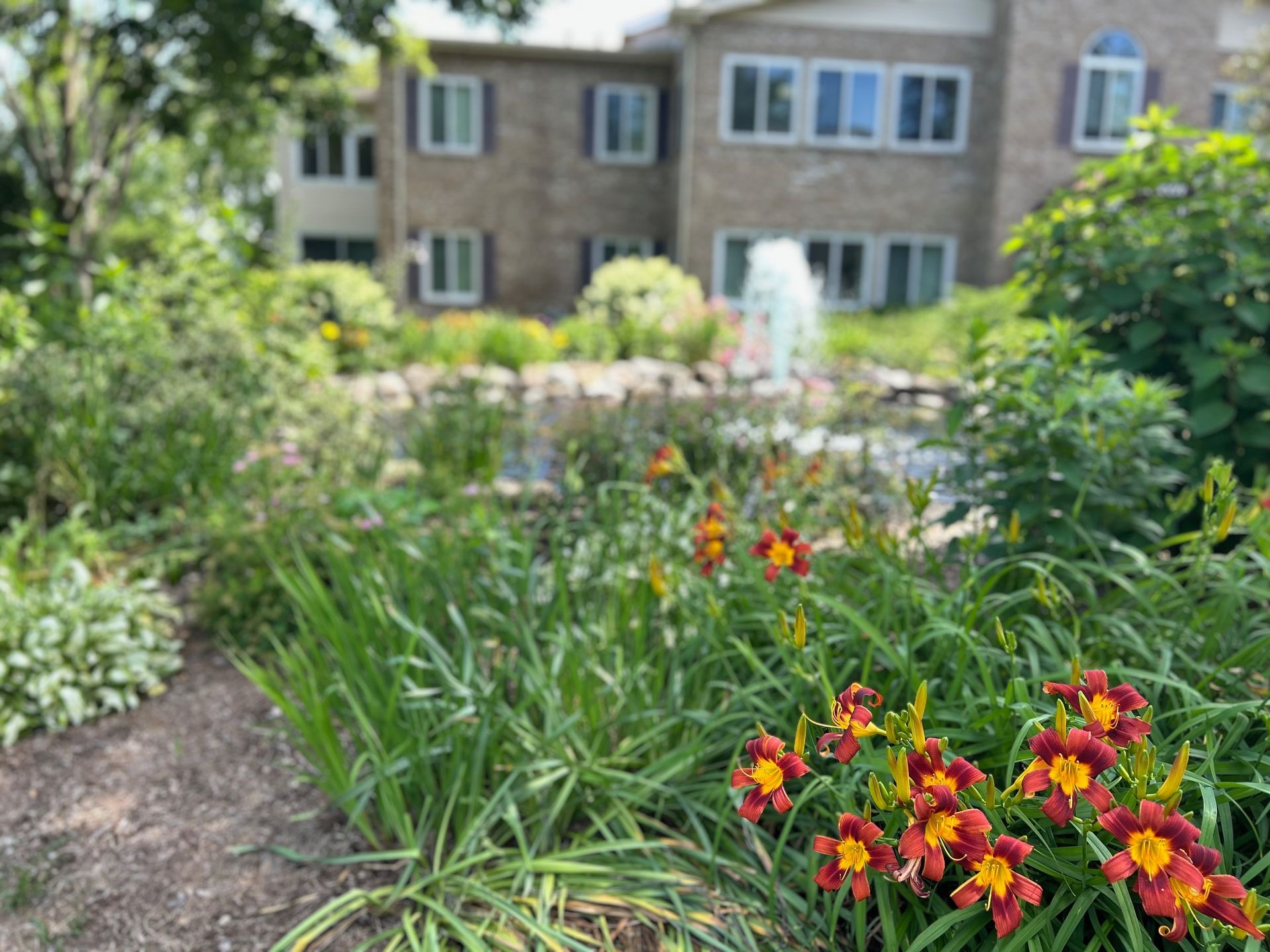 A garden with flowers and a fountain in front of a building.