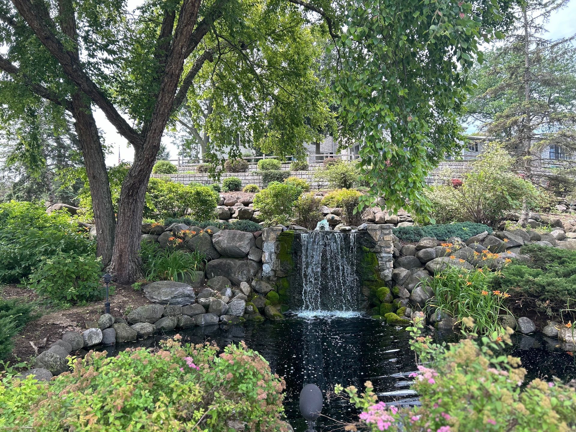 There is a waterfall in the middle of a park surrounded by trees.